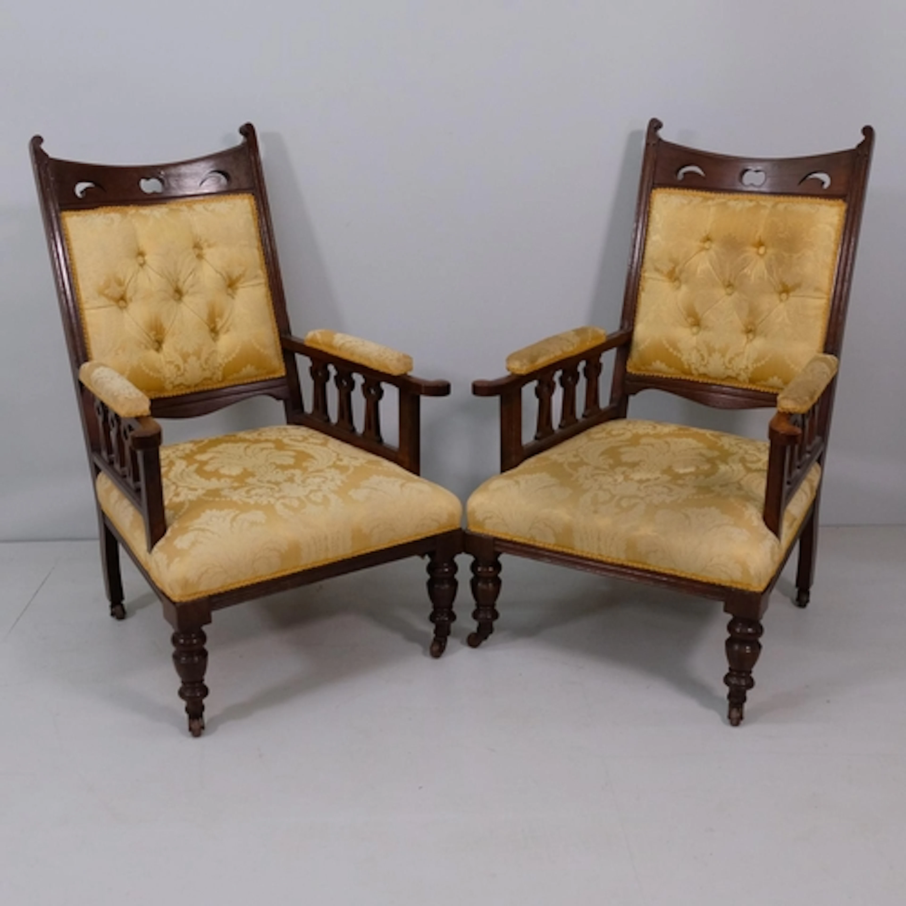 A pair of Arts and Crafts oak and upholstered library armcha...
