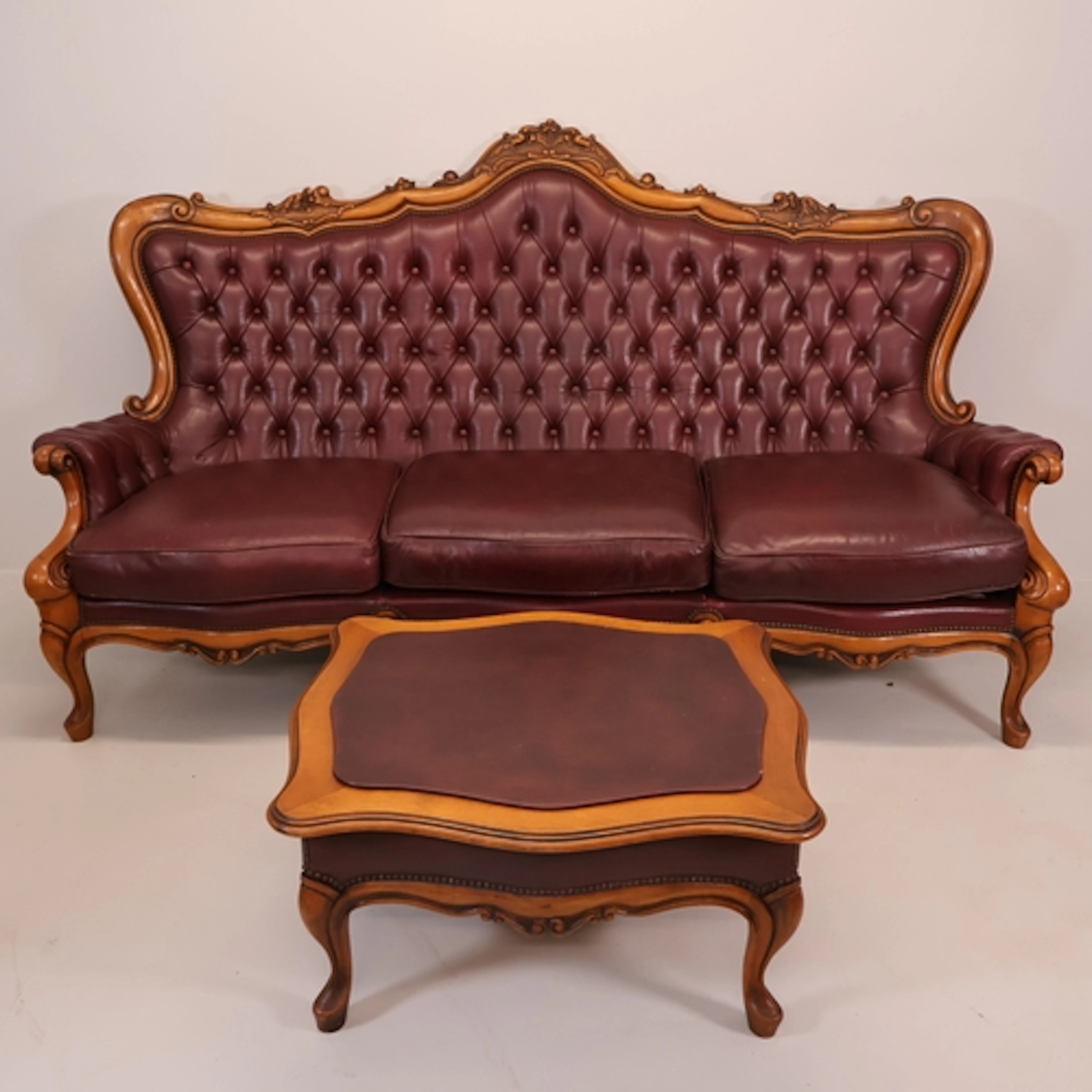 A French Rococo style walnut and button-back leather upholst...