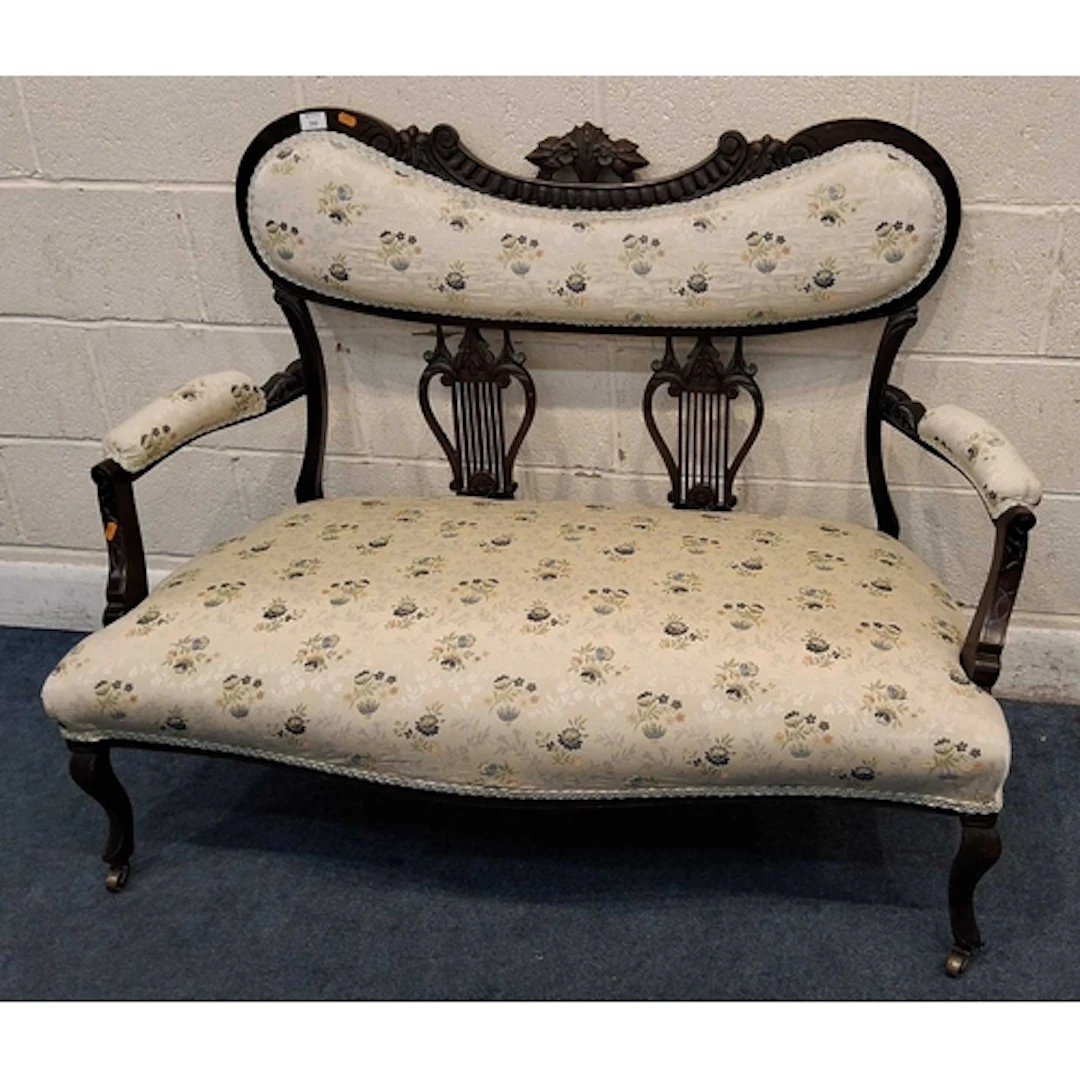 AN EDWARDIAN MAHOGANY SOFA, the backrest with a scrolled and...