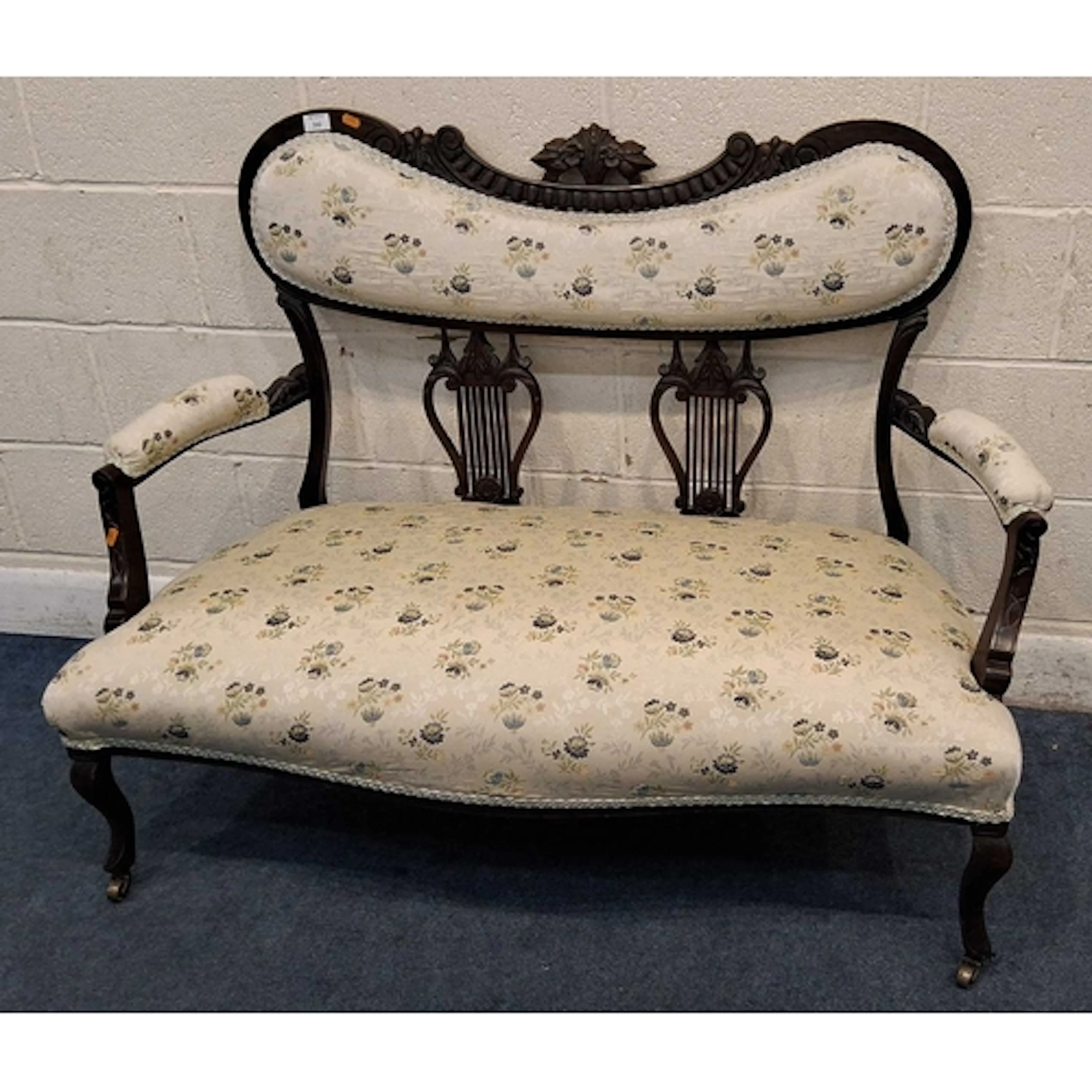 AN EDWARDIAN MAHOGANY SOFA, the backrest with a scrolled and...