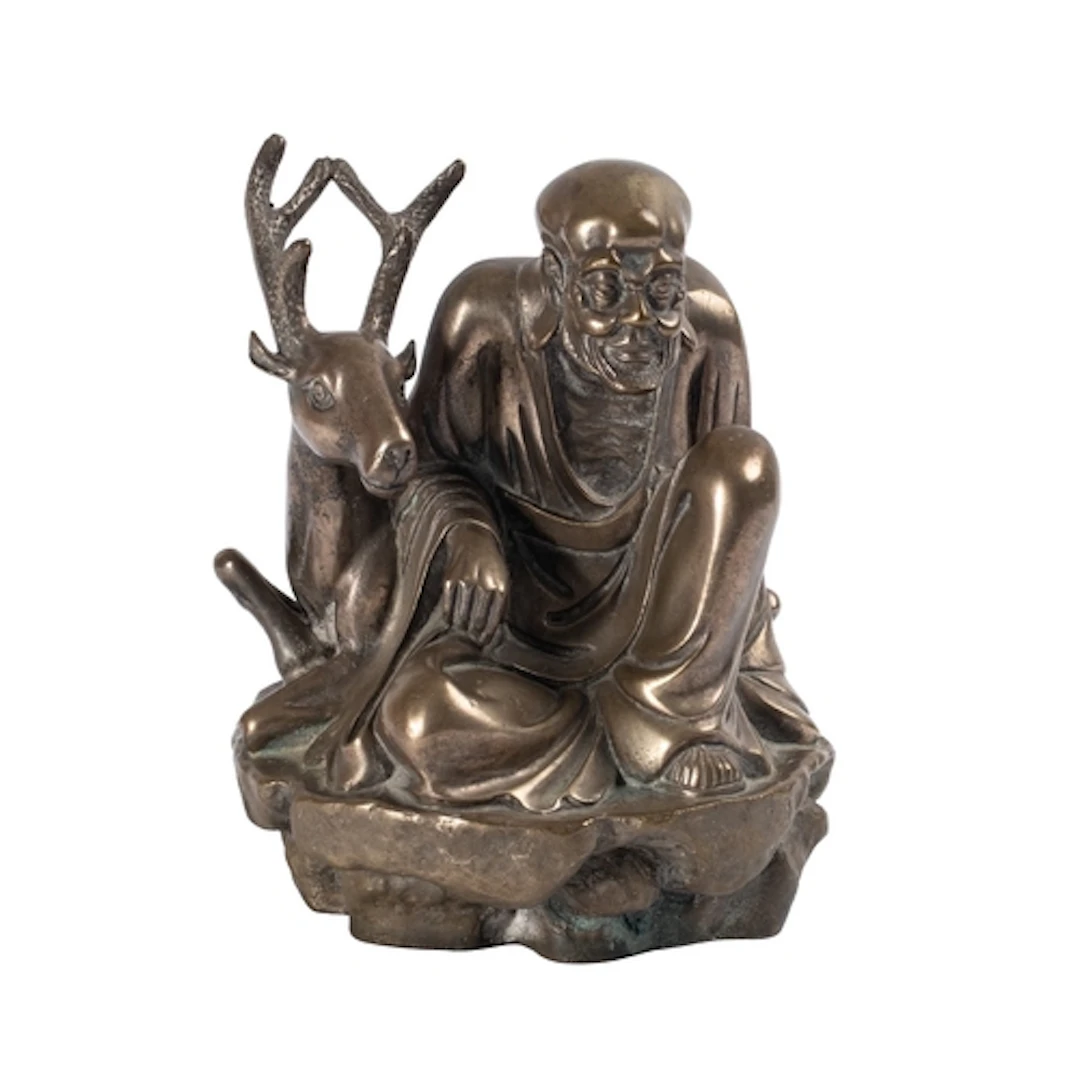 A Chinese polished bronze figure of a seated Immortal with a...