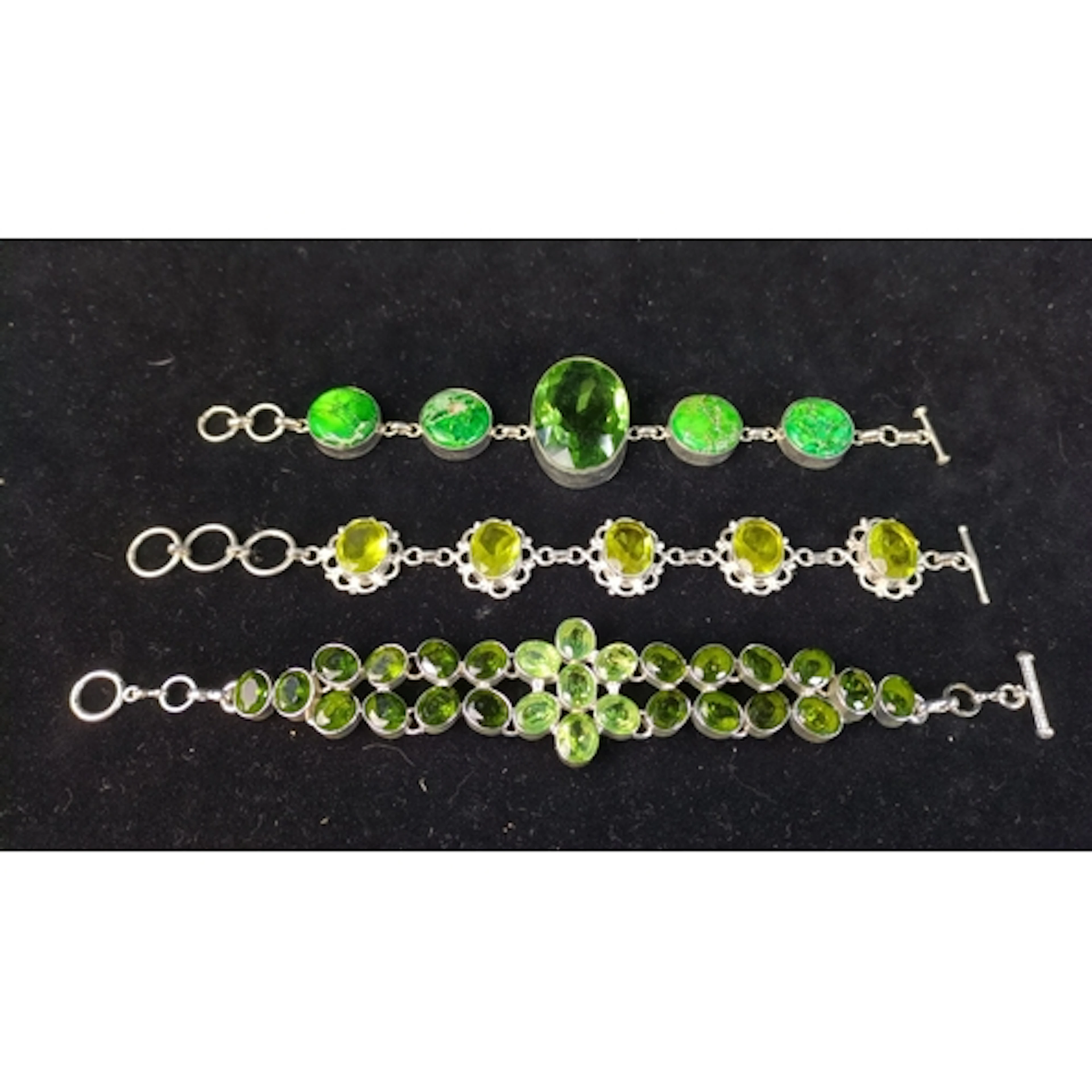 Three silver-tone bracelets: one with green marbled cabochon...