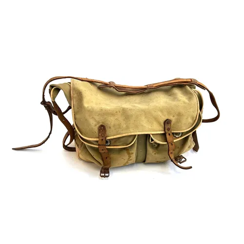 A vintage canvas fishing bag containing a quantity of fishin...