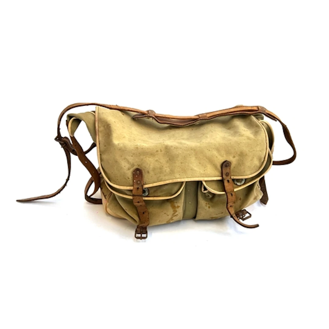 A vintage canvas fishing bag containing a quantity of fishin...