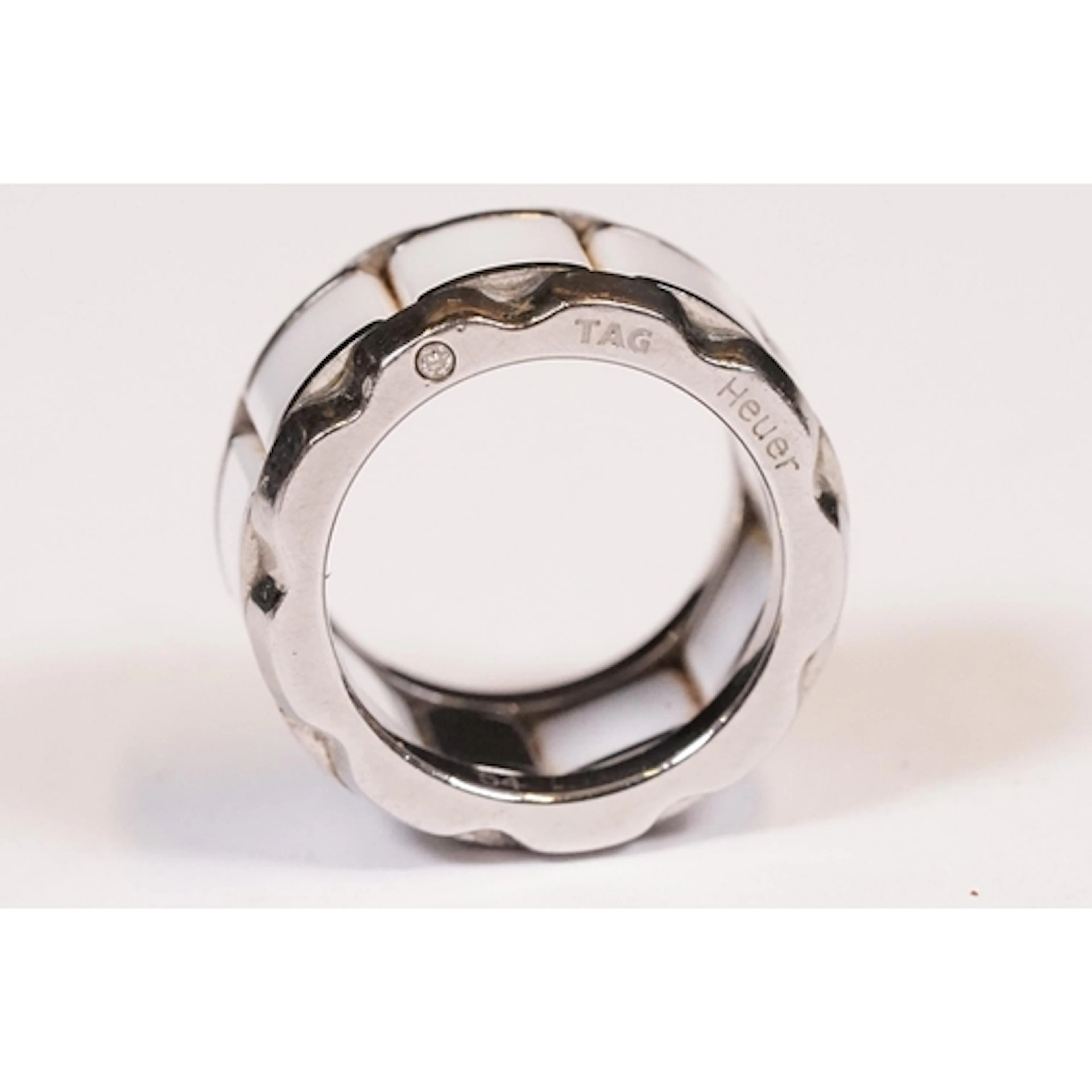 A white metal ring set with white ceramic panels by Tag Heue...