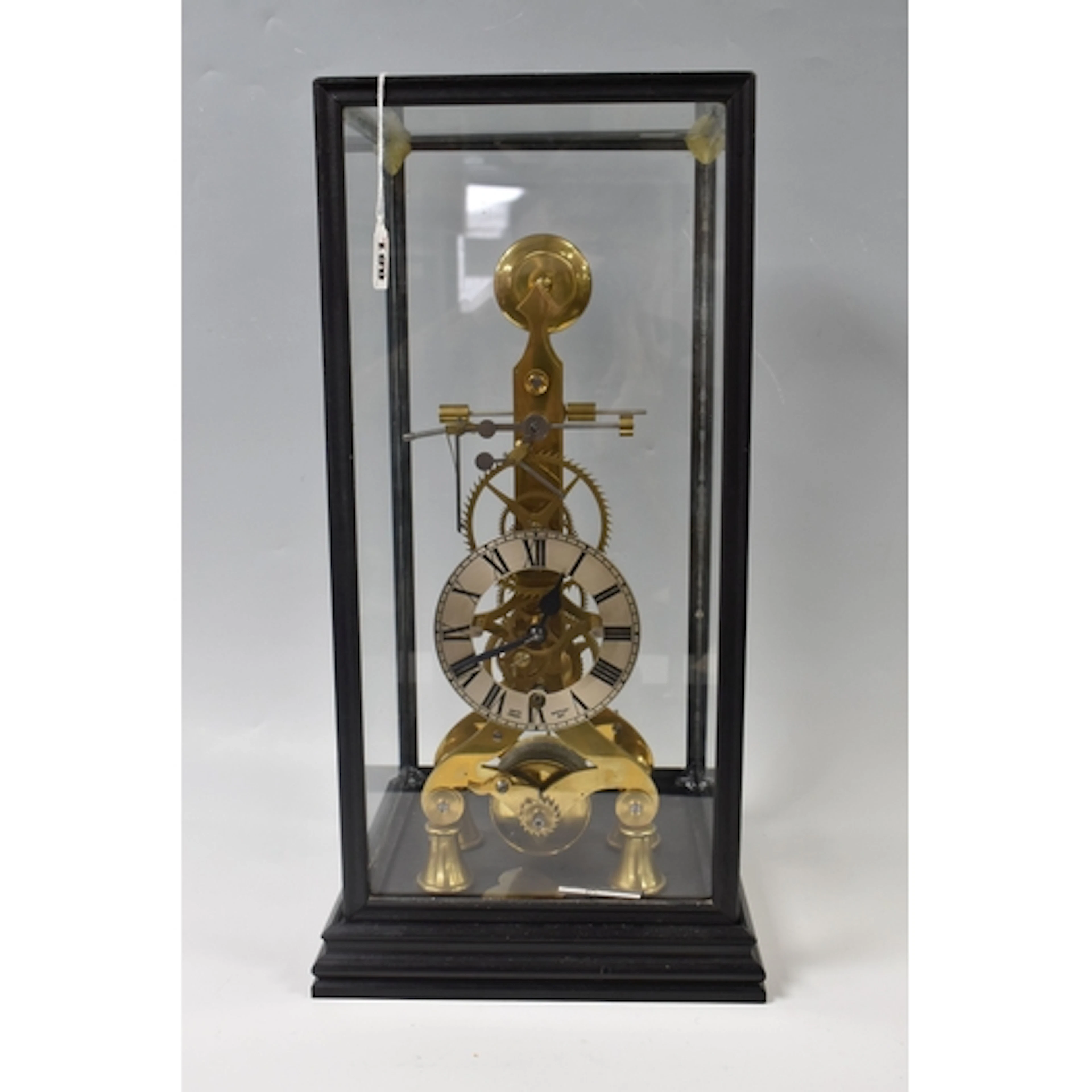 A CASED SKELETON CLOCK mostly in brass with a printed clock ...