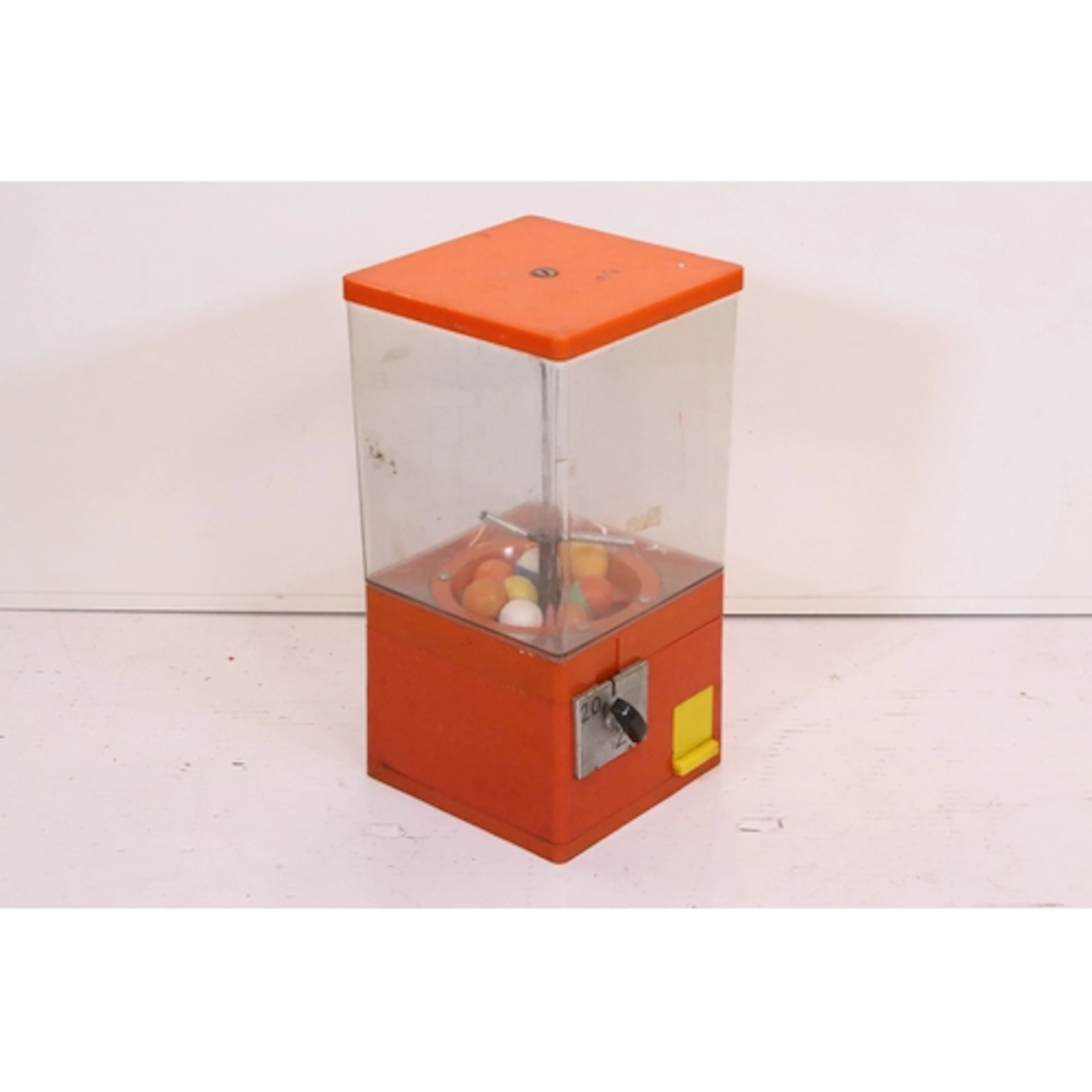 Mid 20th century gumball machine, having orange plastic body...