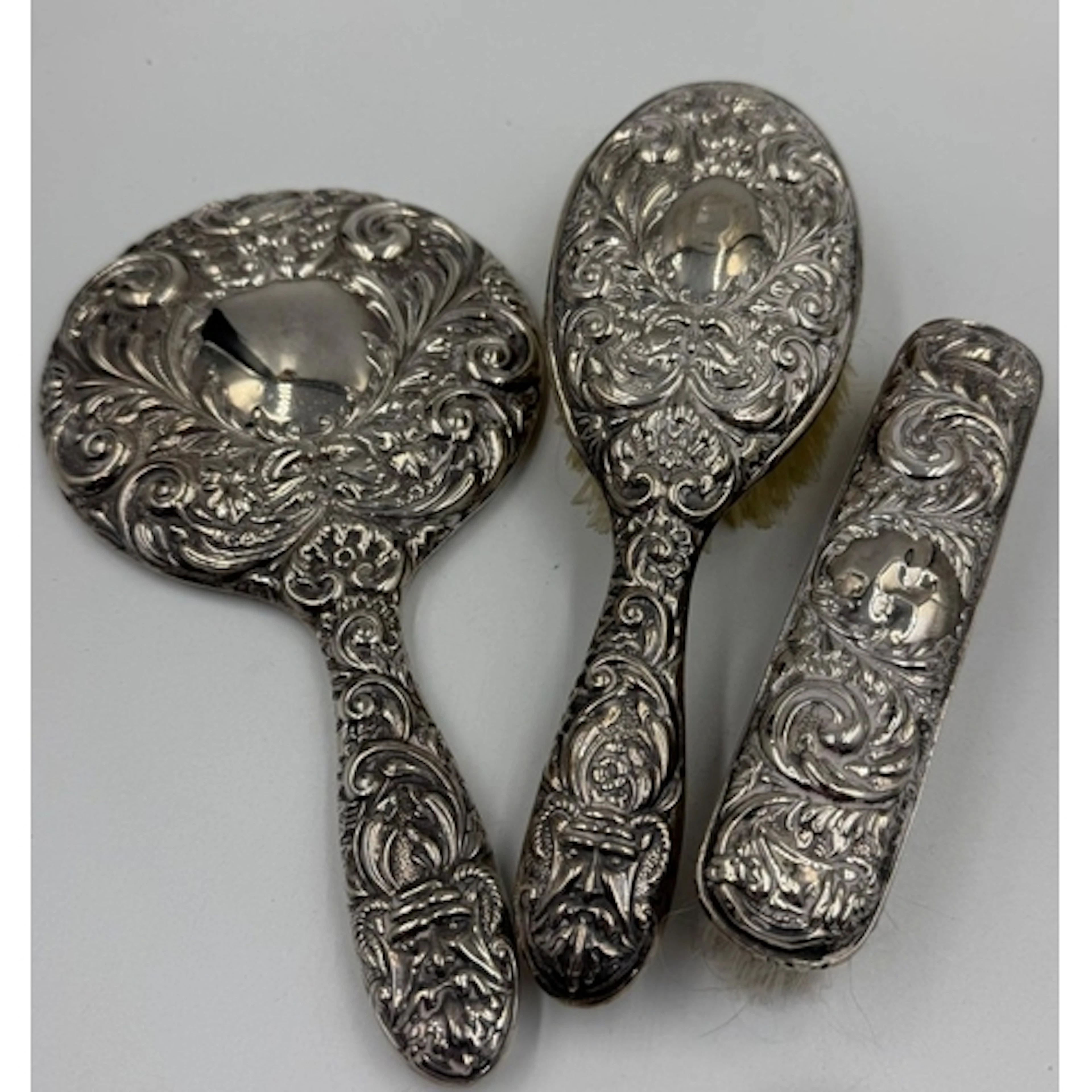A three piece silver backed vanity set to include: two brush...