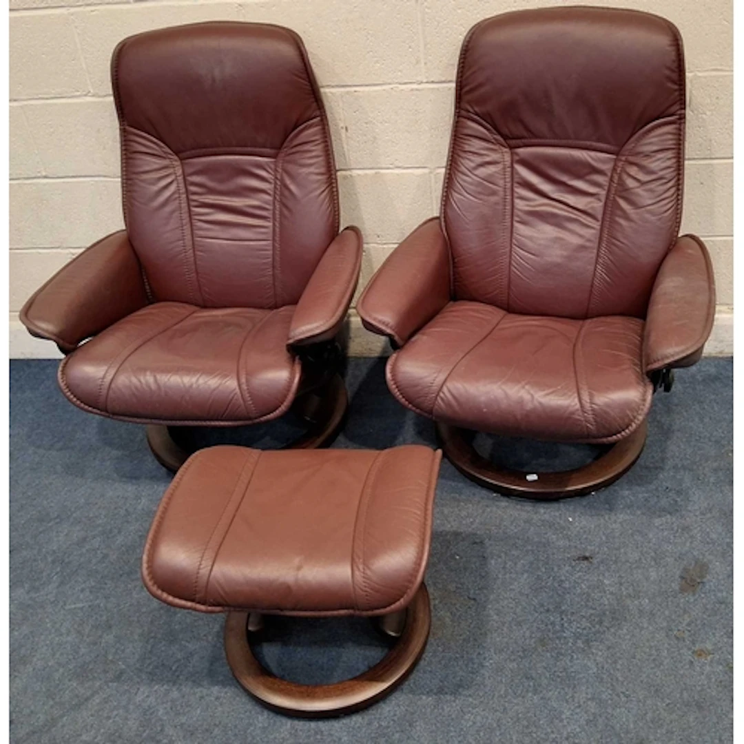 A PAIR OF EKORNESS STRESSLESS BURGUNDY LEATHER SWIVEL RECLIN...