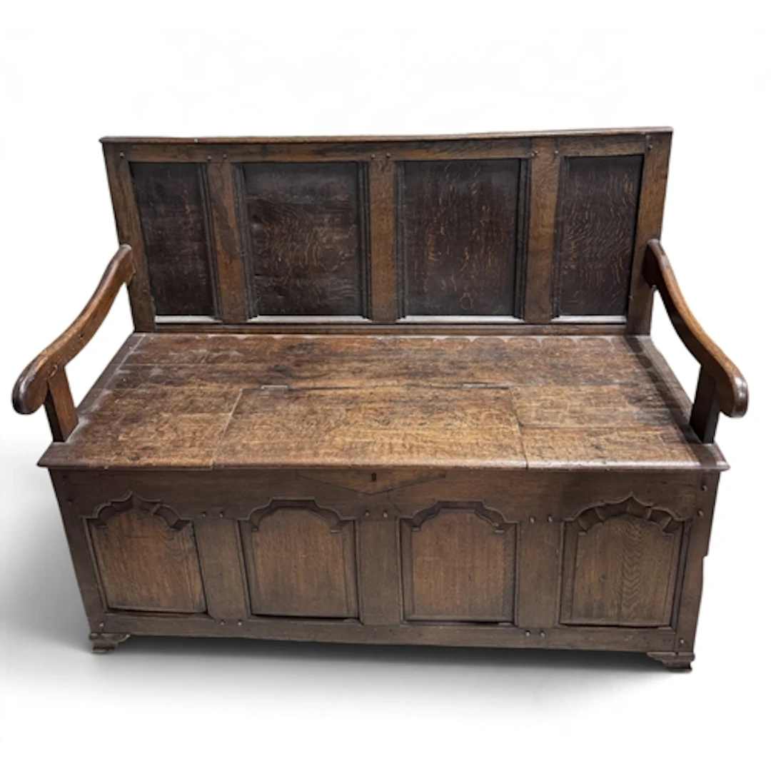 AN 18TH CENTURY OAK HALL SETTLE WITH PANELLED FRONT The seat...