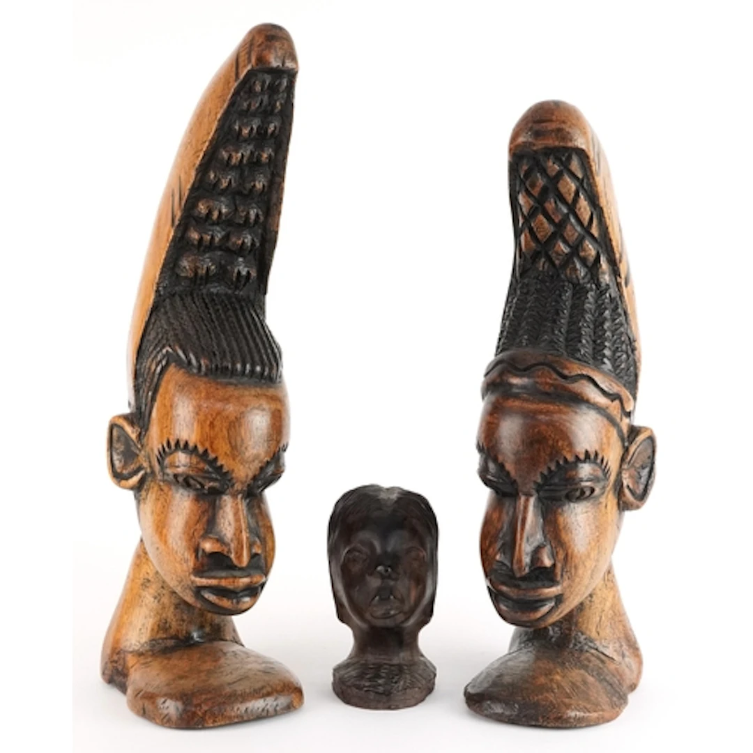 Three hand carved wooden busts of African women, two with el...