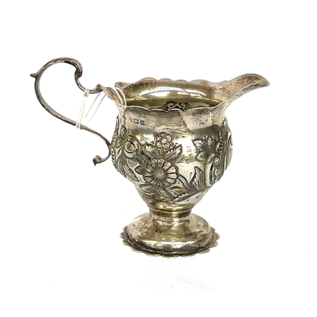 A chased silver milk jug by William Aitken, Birmingham 1909,...
