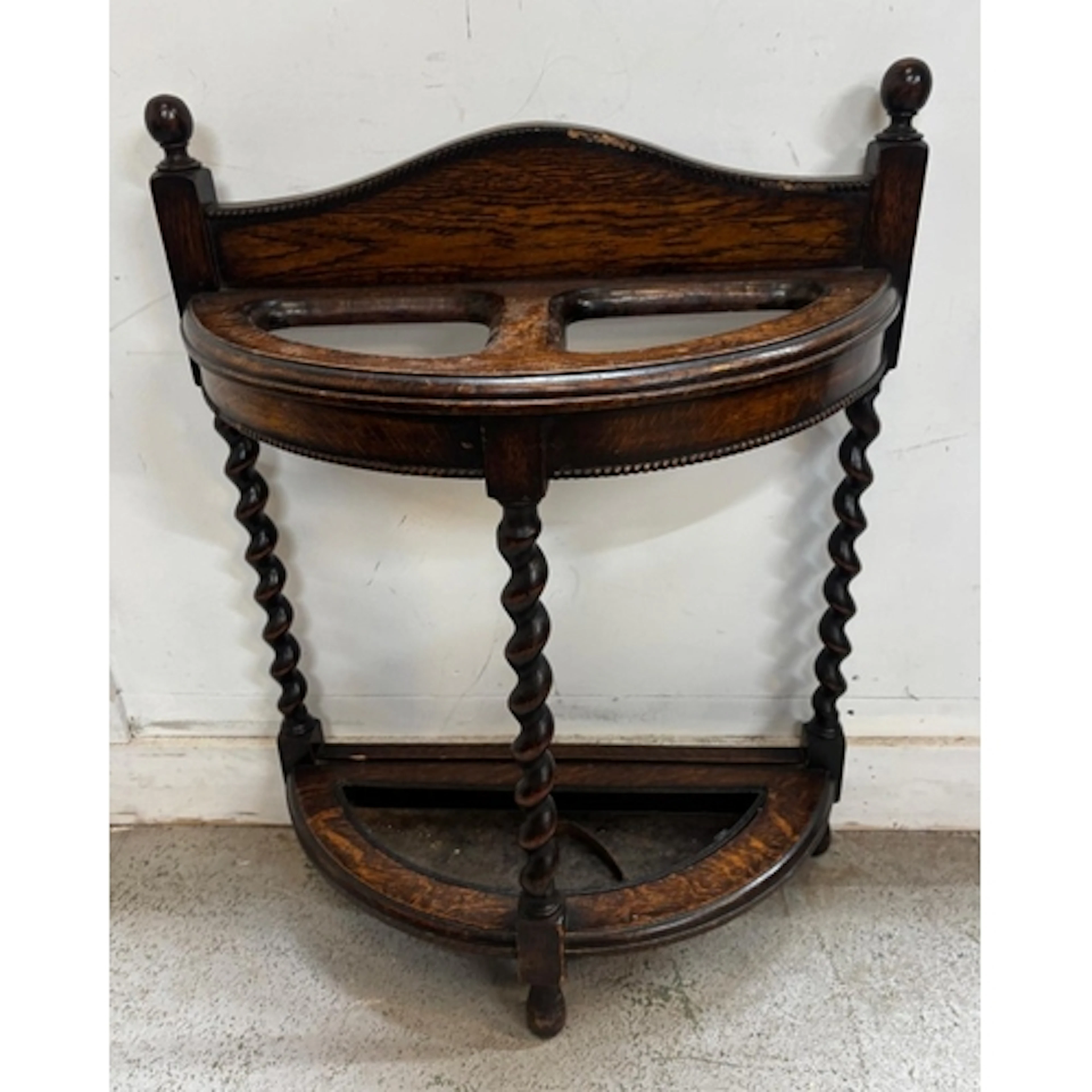A 1920's oak barley twist stick stand in a half-moon shape w...
