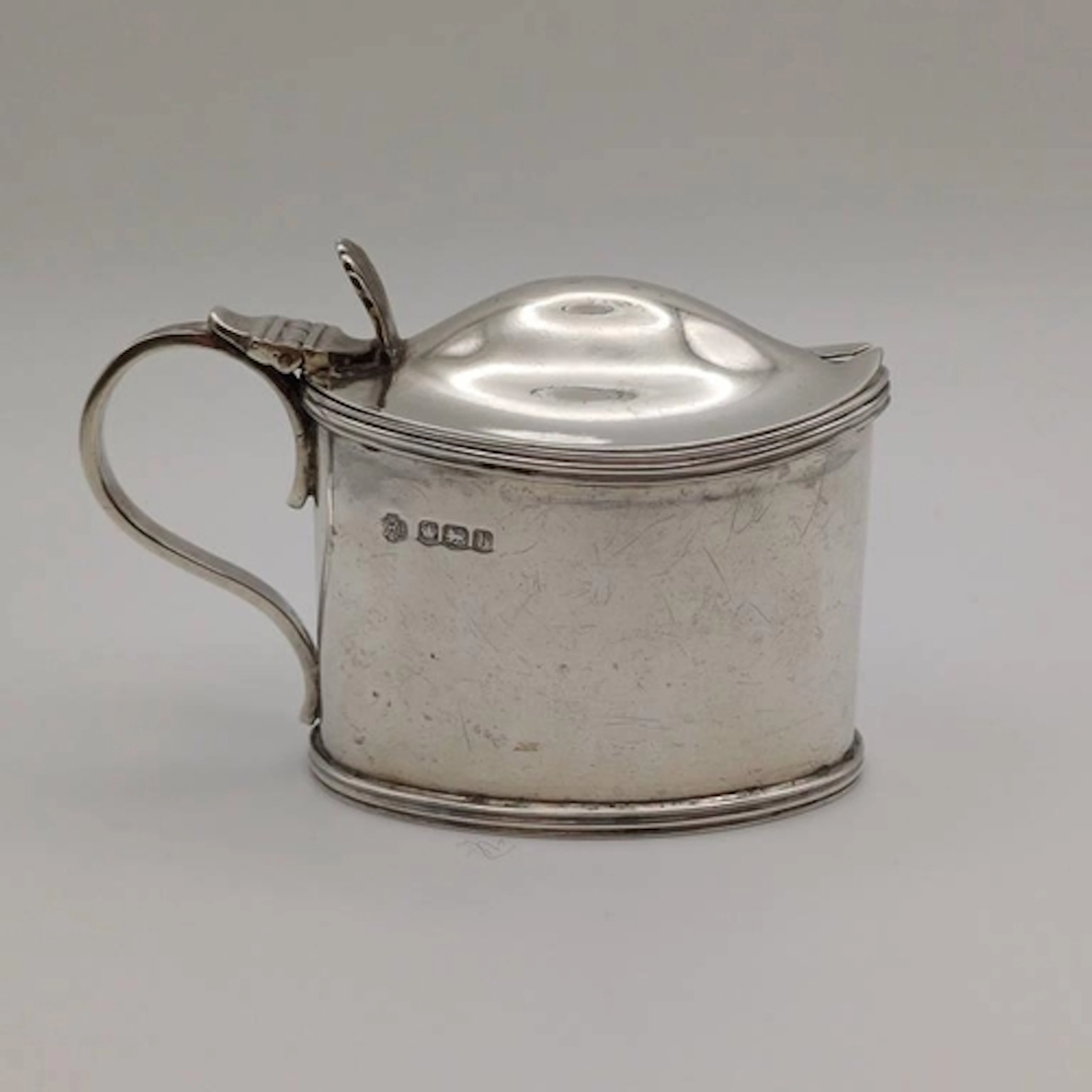 A SILVER MUSTARD POT WITH BLUE GLASS LINER BY WILLIAM HUTTON...