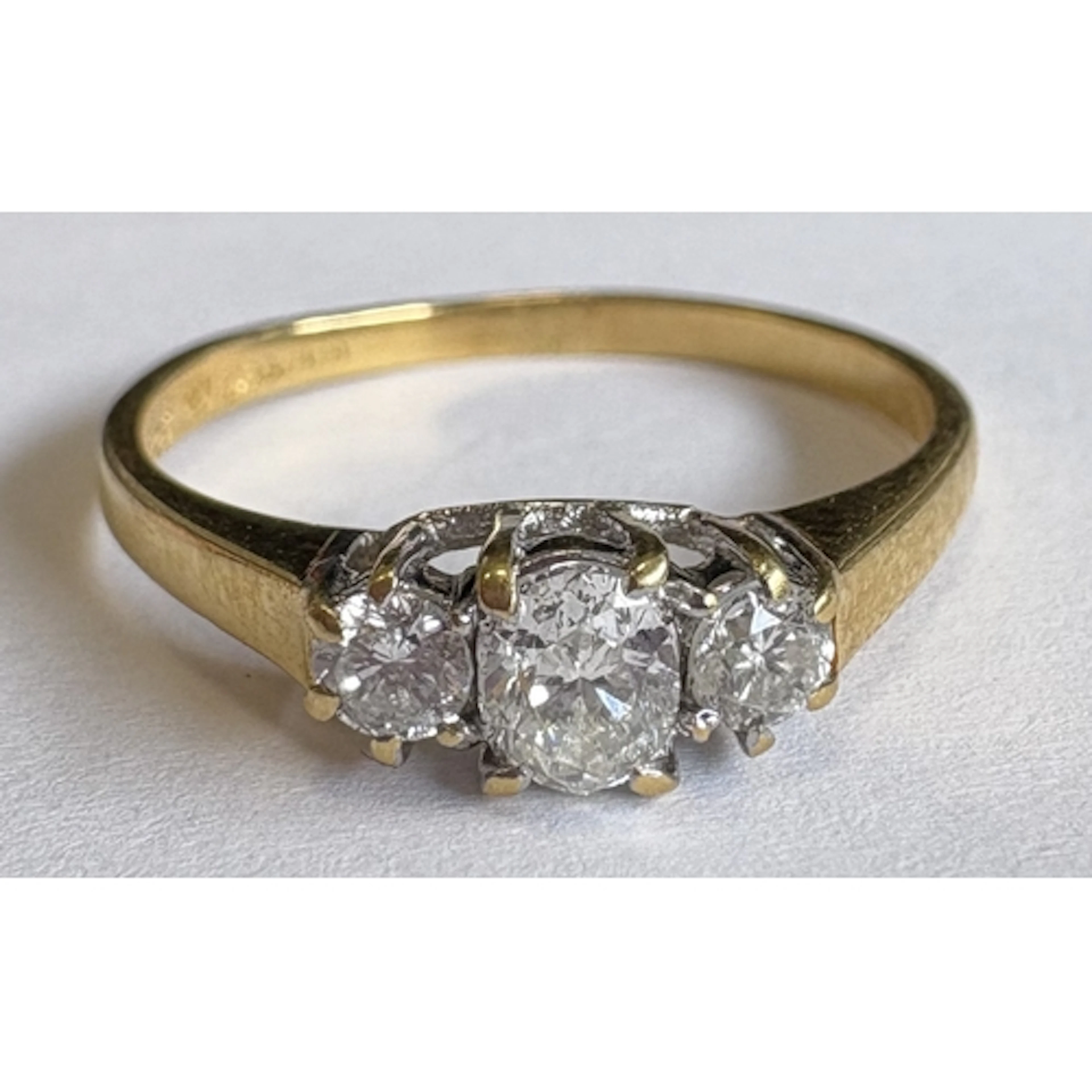 An oval three-stone diamond ring in 18 carat gold and platin...