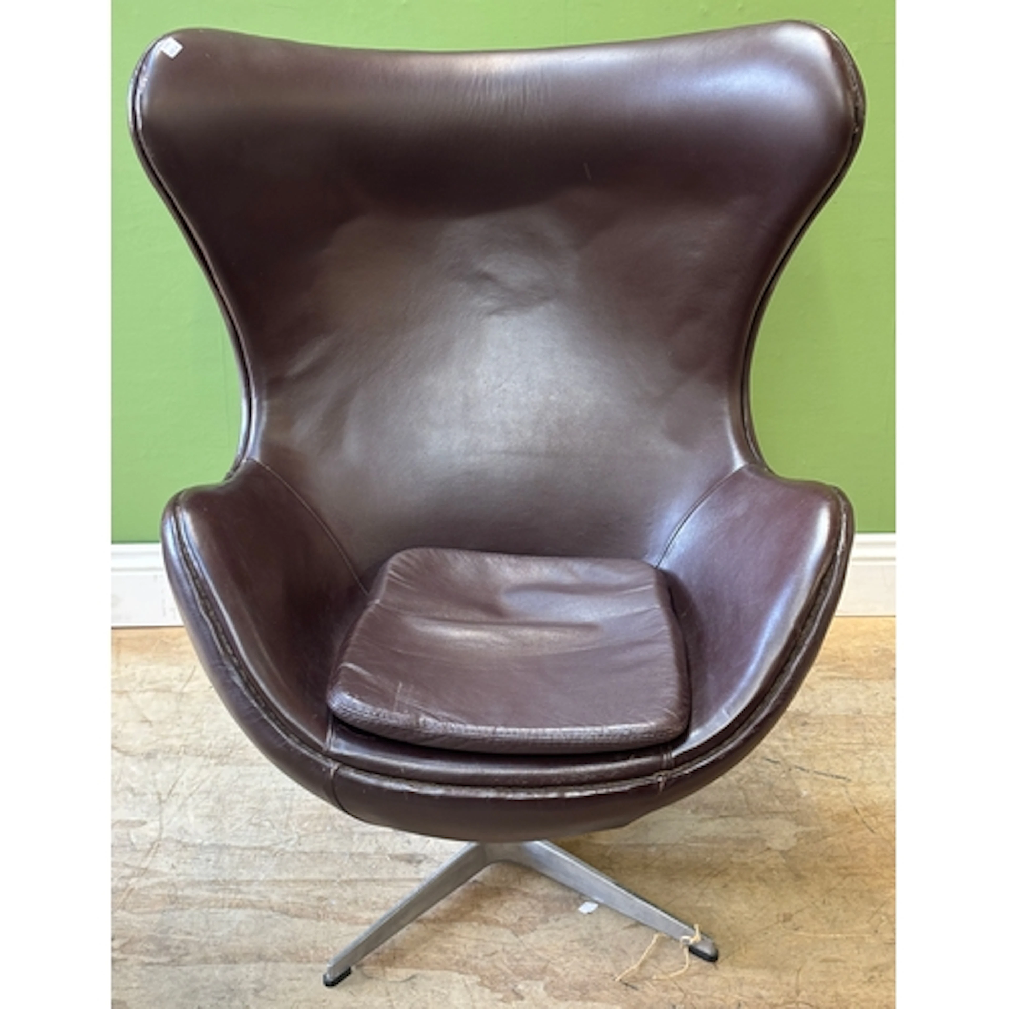 An Arne Jacobsen style brown leather swivel egg chair on alu...