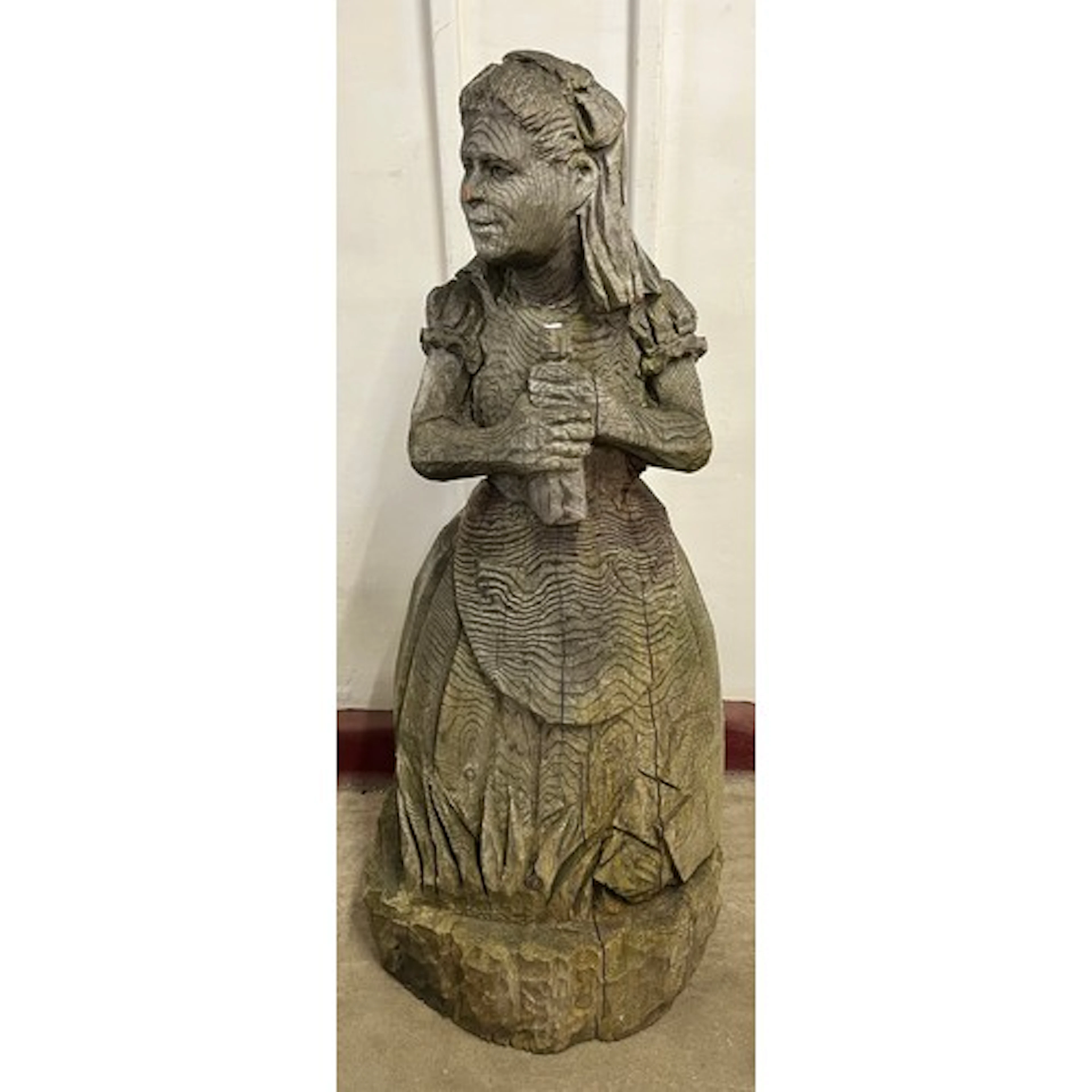 A large carved wooden sculpture of Alice in Wonderland
