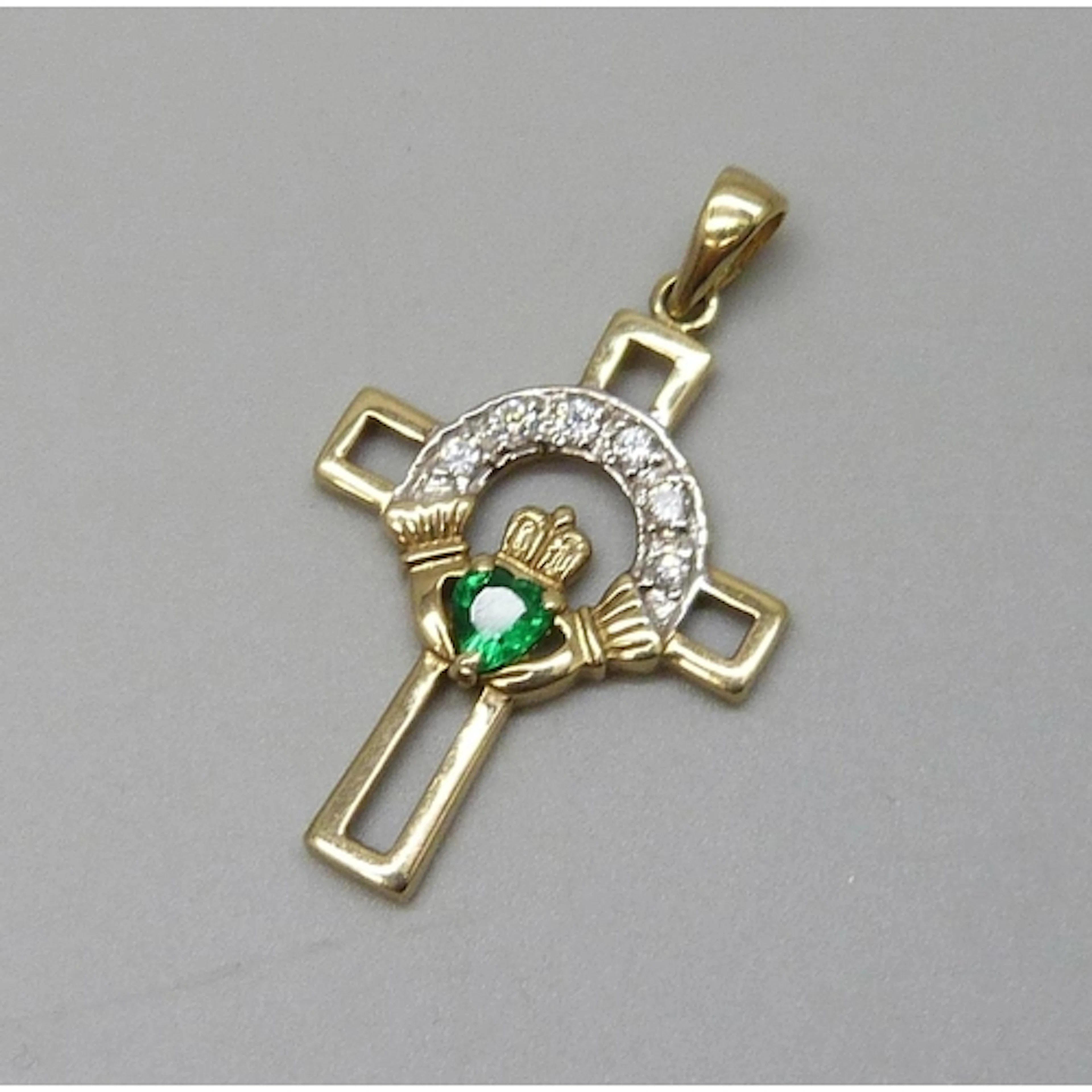 A 9ct gold Claddagh necklace pendant set with green and whit...