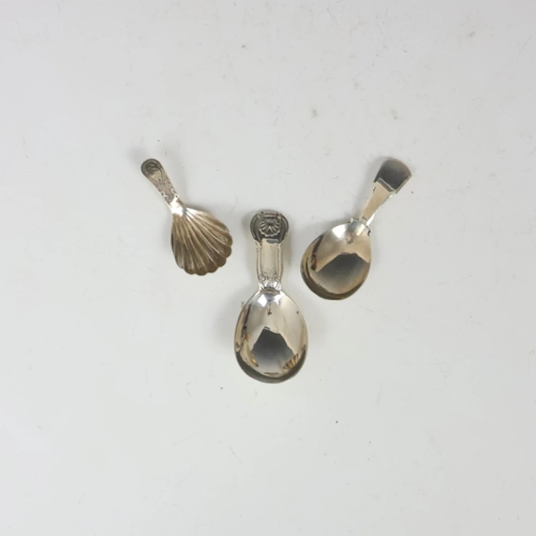 A group of three silver caddy spoons, including a 19th centu...
