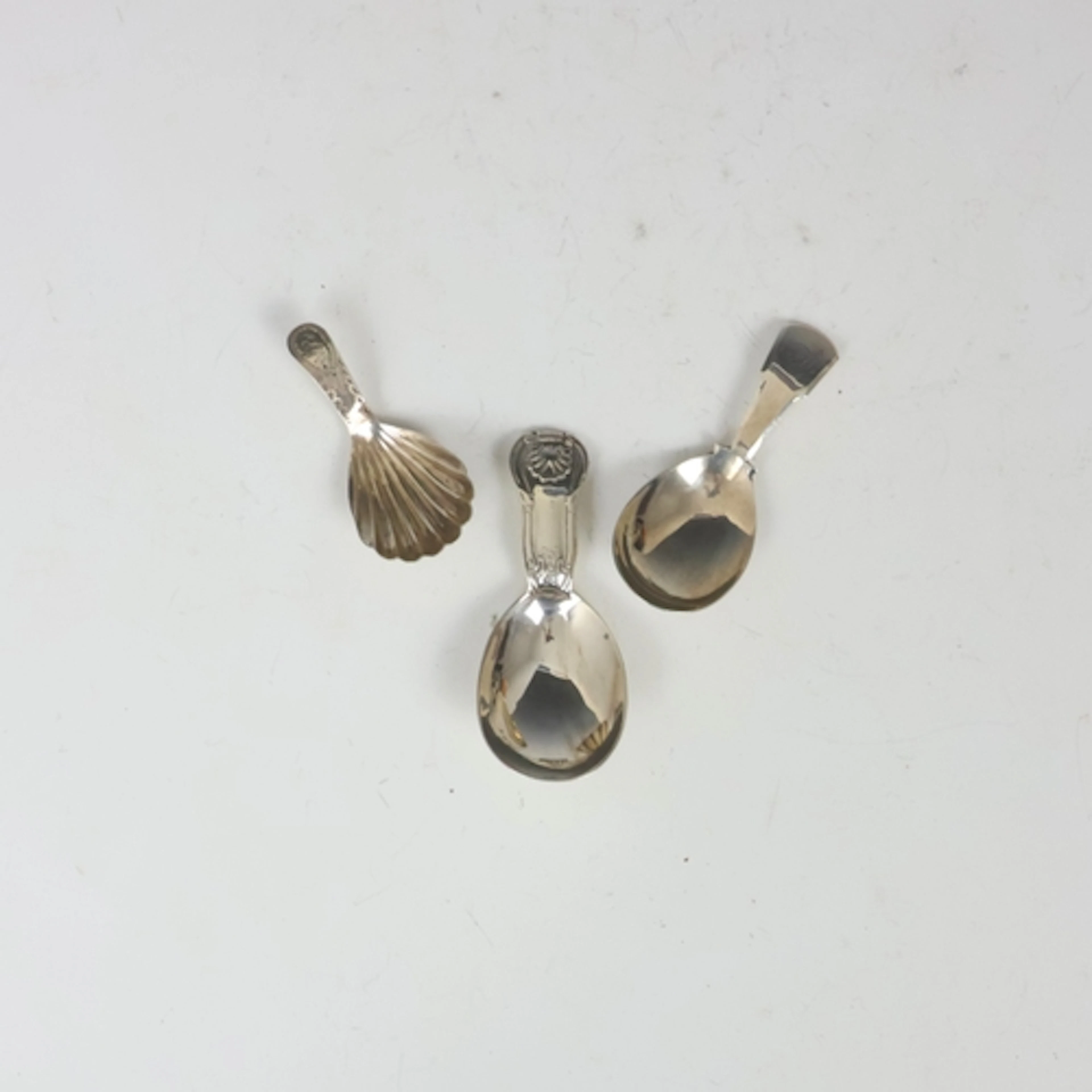 A group of three silver caddy spoons, including a 19th centu...