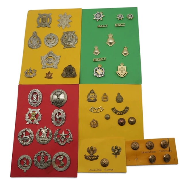 A collection of military cap badges and uniform buttons, inc...