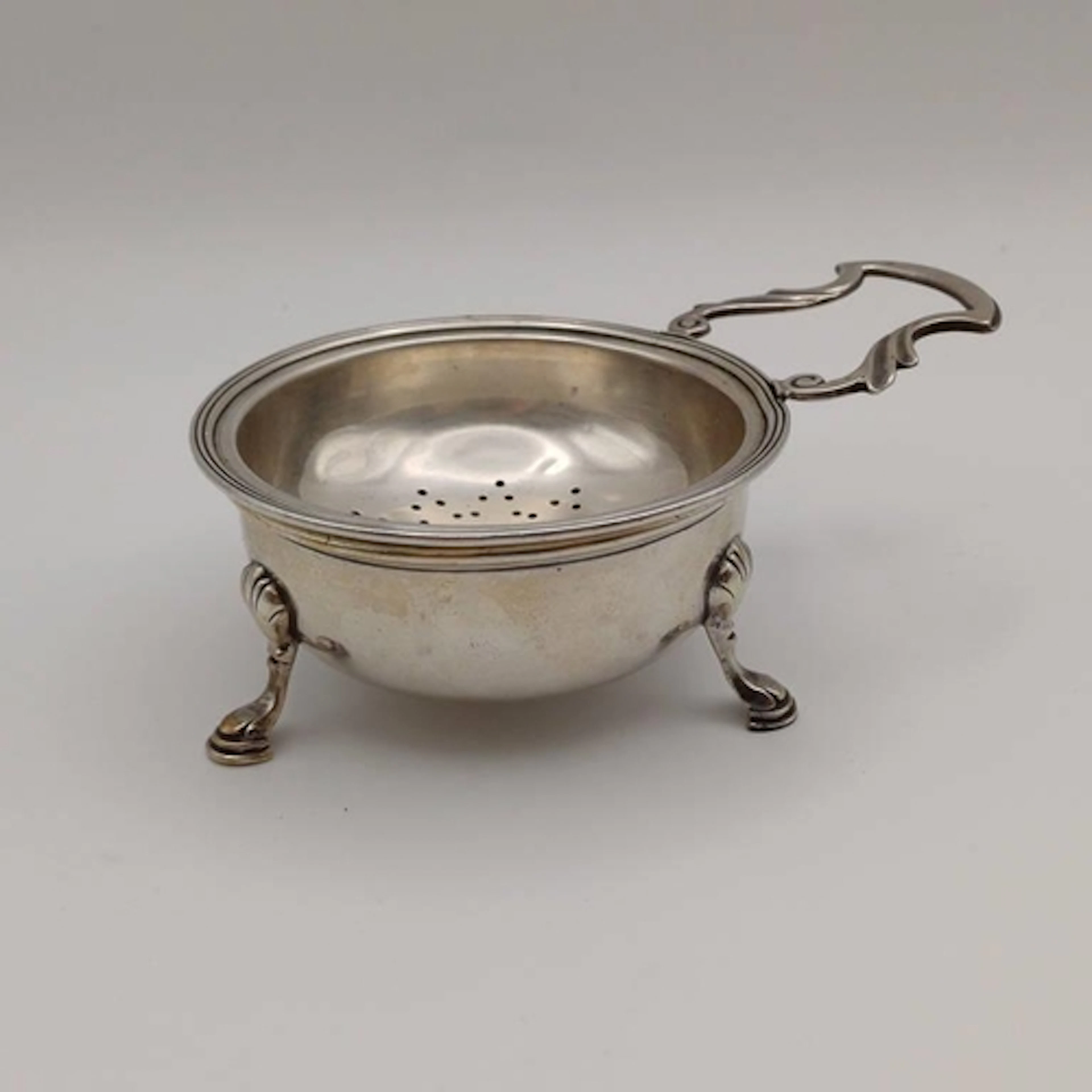 AN AMERICAN SILVER TEA STRAINER ON 3 HOOF FEET MARKED STERLI...