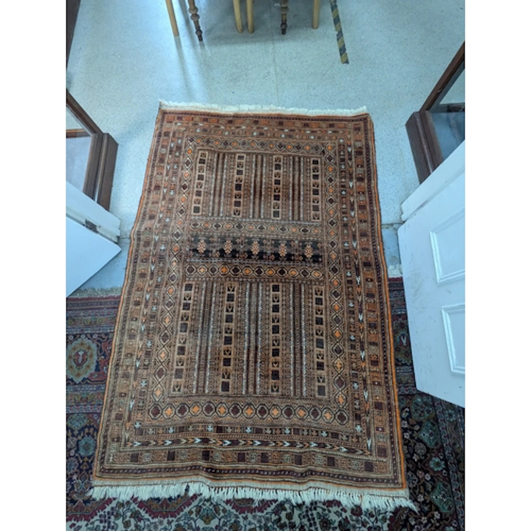 An Afghan tribal rug with geometric motifs in orange and bro...