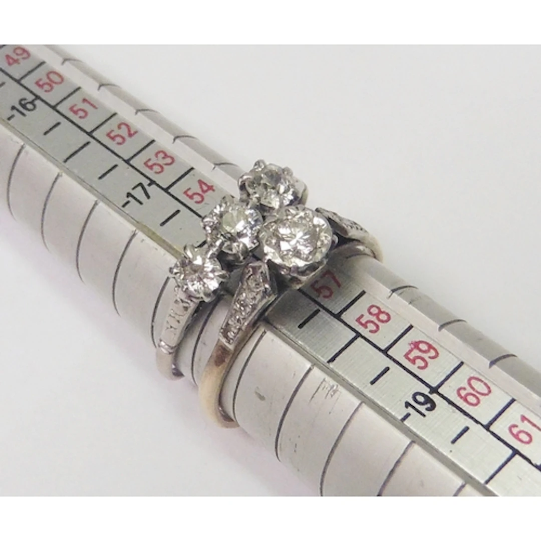 A diamond trilogy ring in an unmarked white metal setting; a...