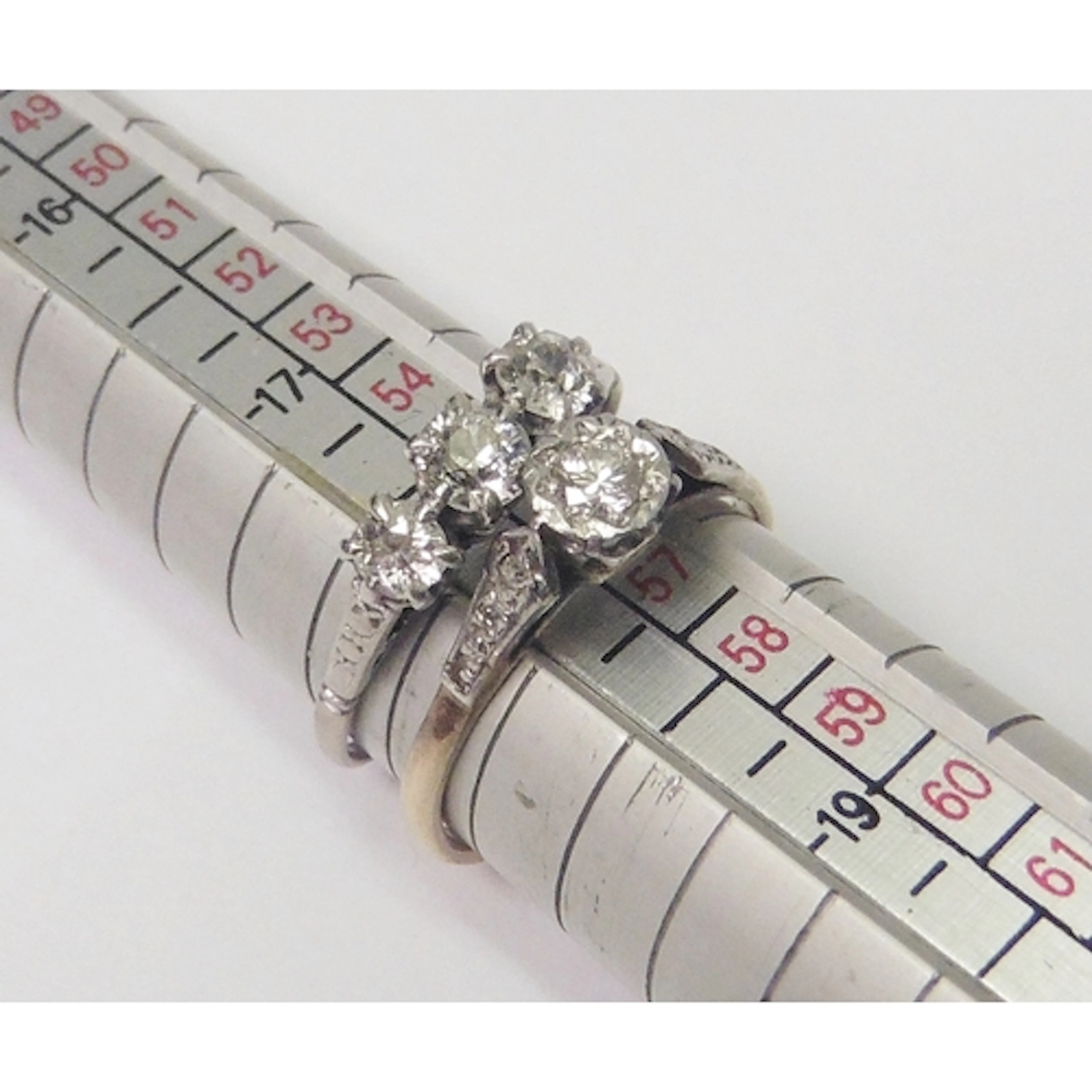 A diamond trilogy ring in an unmarked white metal setting; a...