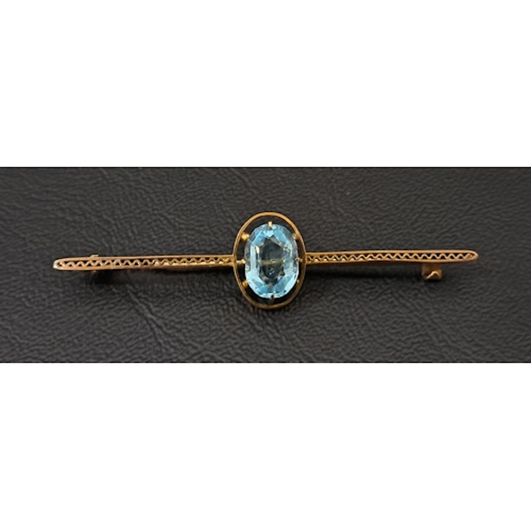 NINE CARAT GOLD BAR BROOCH set with central faceted blue gla...