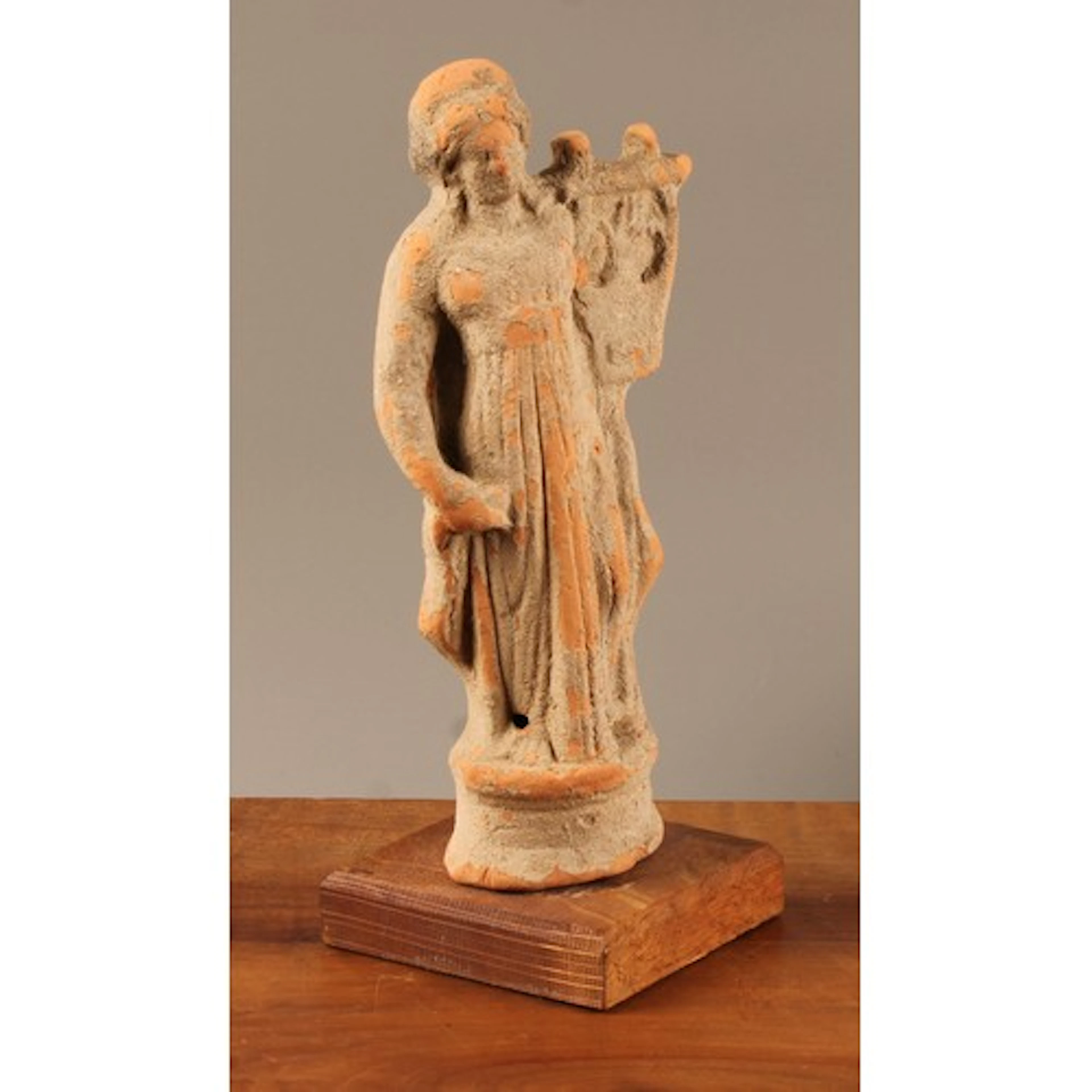 A terracotta Tanagra type votive figure, as Apollo holding a...