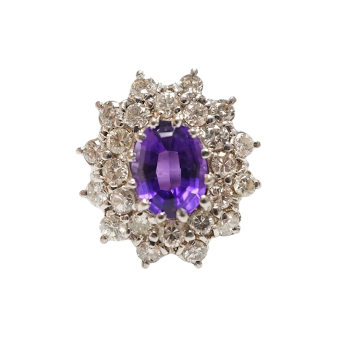 An amethyst and diamond ring, claw-set with an oval amethyst...