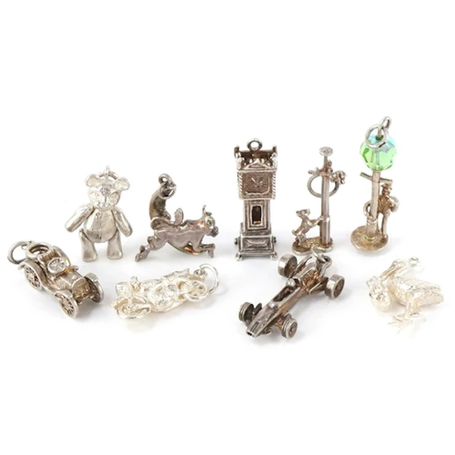 A collection of silver charms including a cow jumping over t...