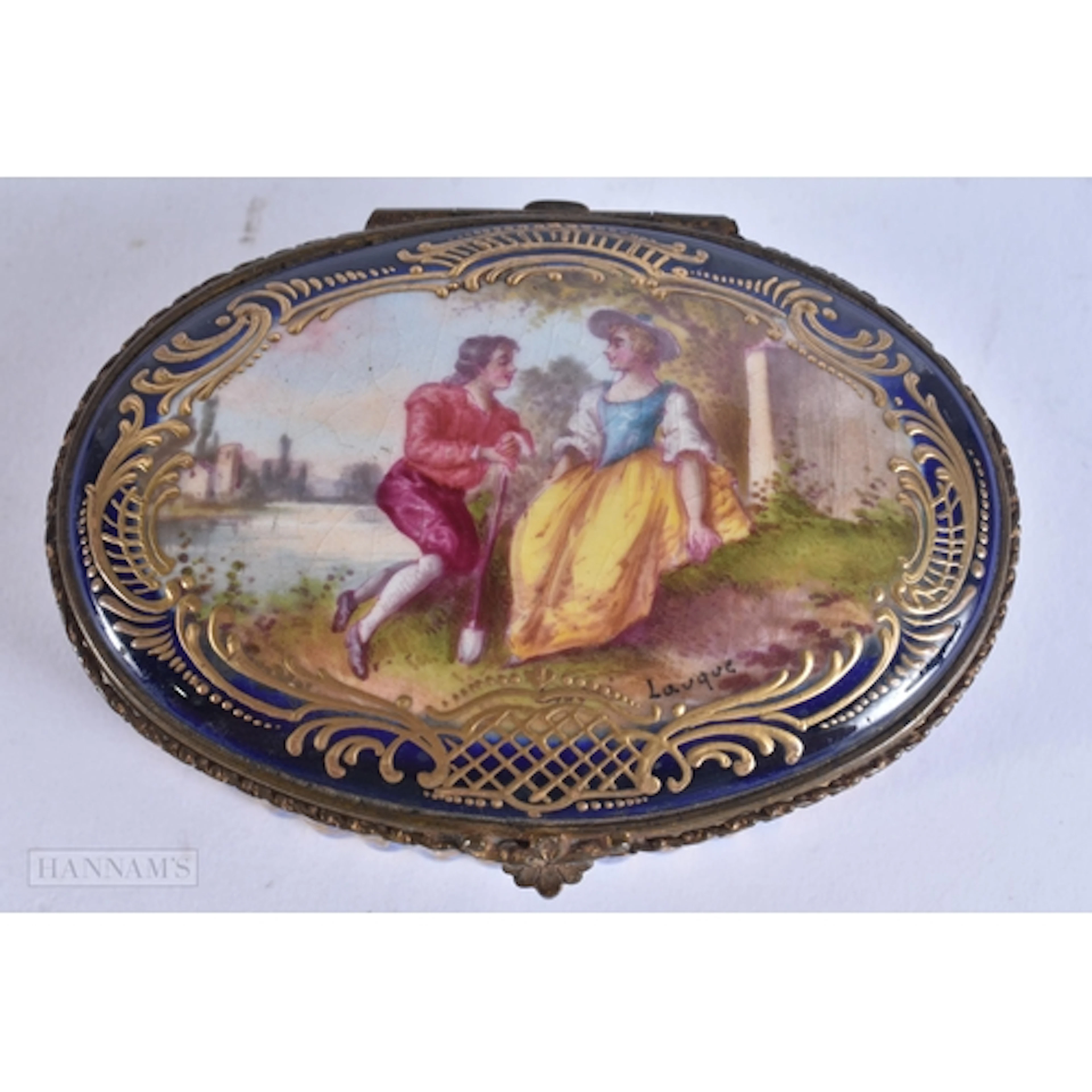 AN ANTIQUE FRENCH PORCELAIN BOX painted with lovers in a lan...