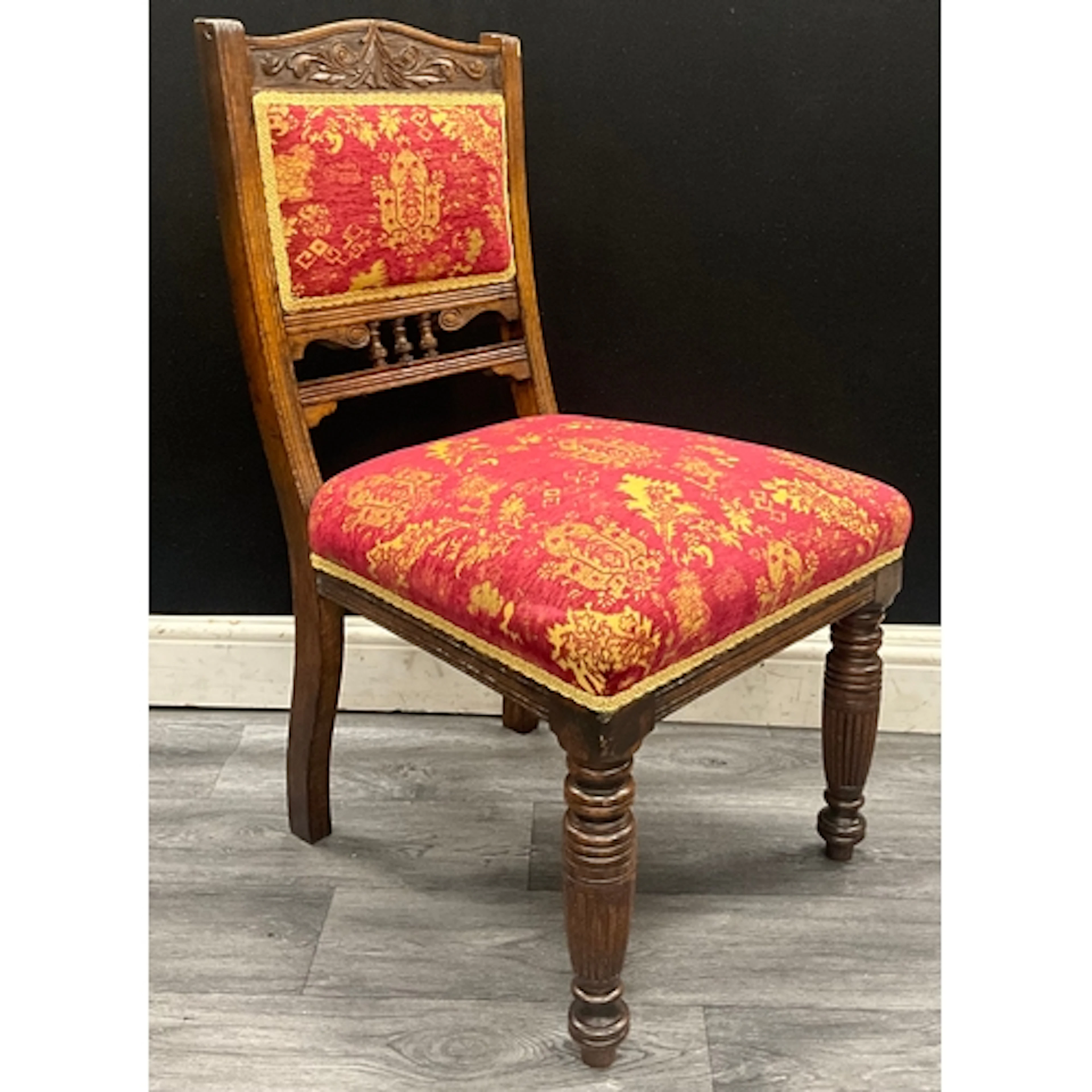 A late Victorian dark oak side chair with scrolled crest car...