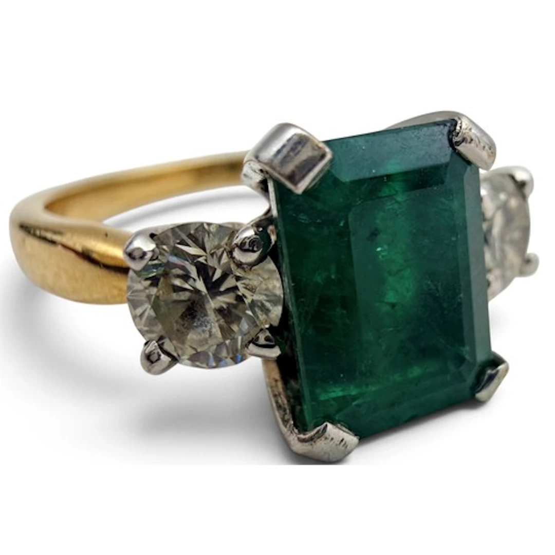 An emerald and diamond ring, the central emerald-cut emerald...