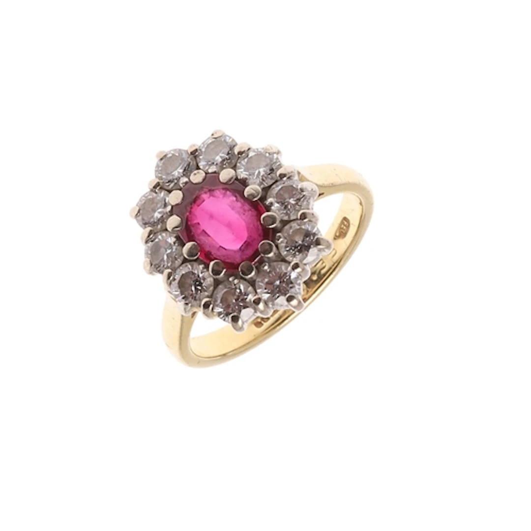 A RUBY AND DIAMOND CLUSTER RING. the oval-shaped ruby is set...