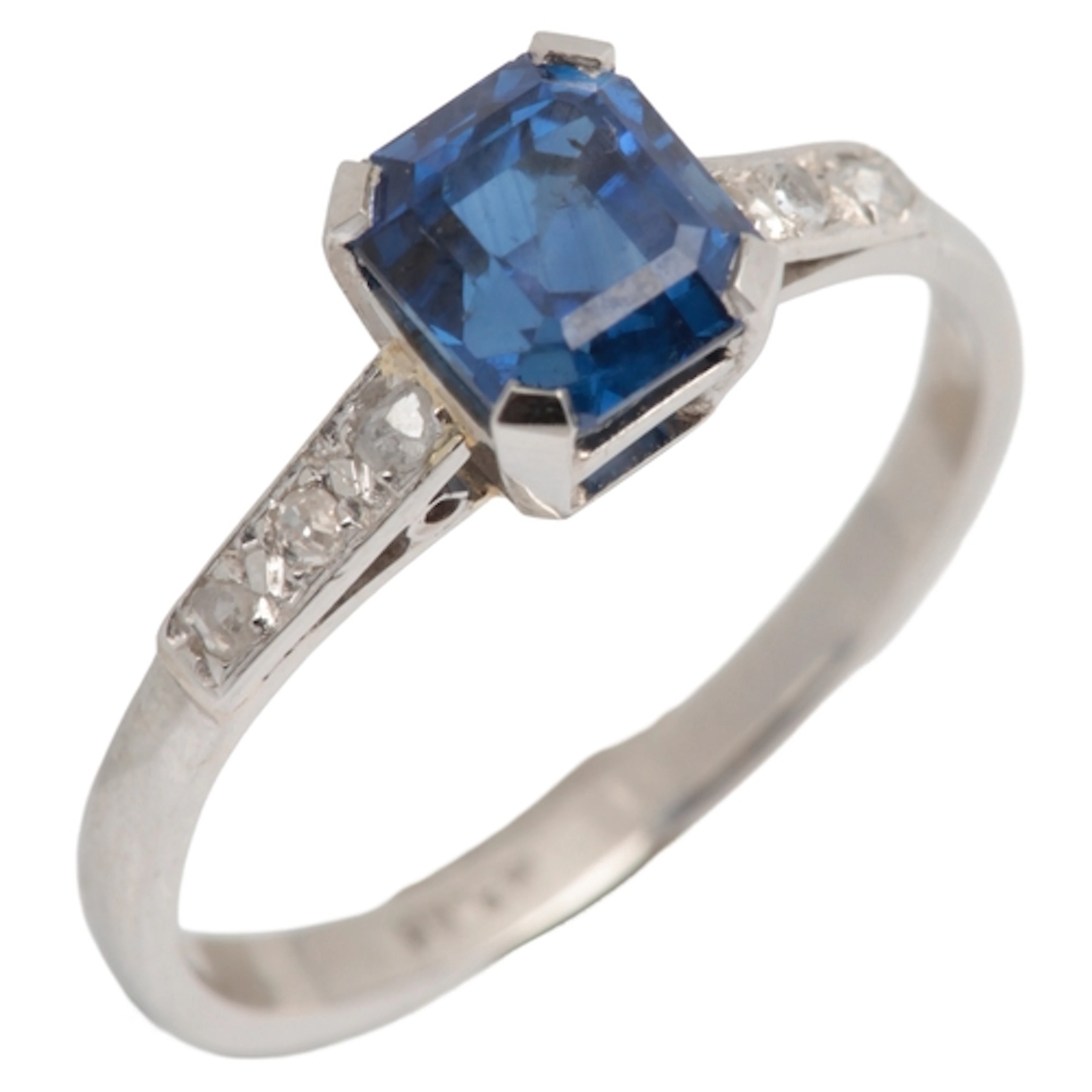 A sapphire and diamond ring, claw-set with a step-cut sapphi...