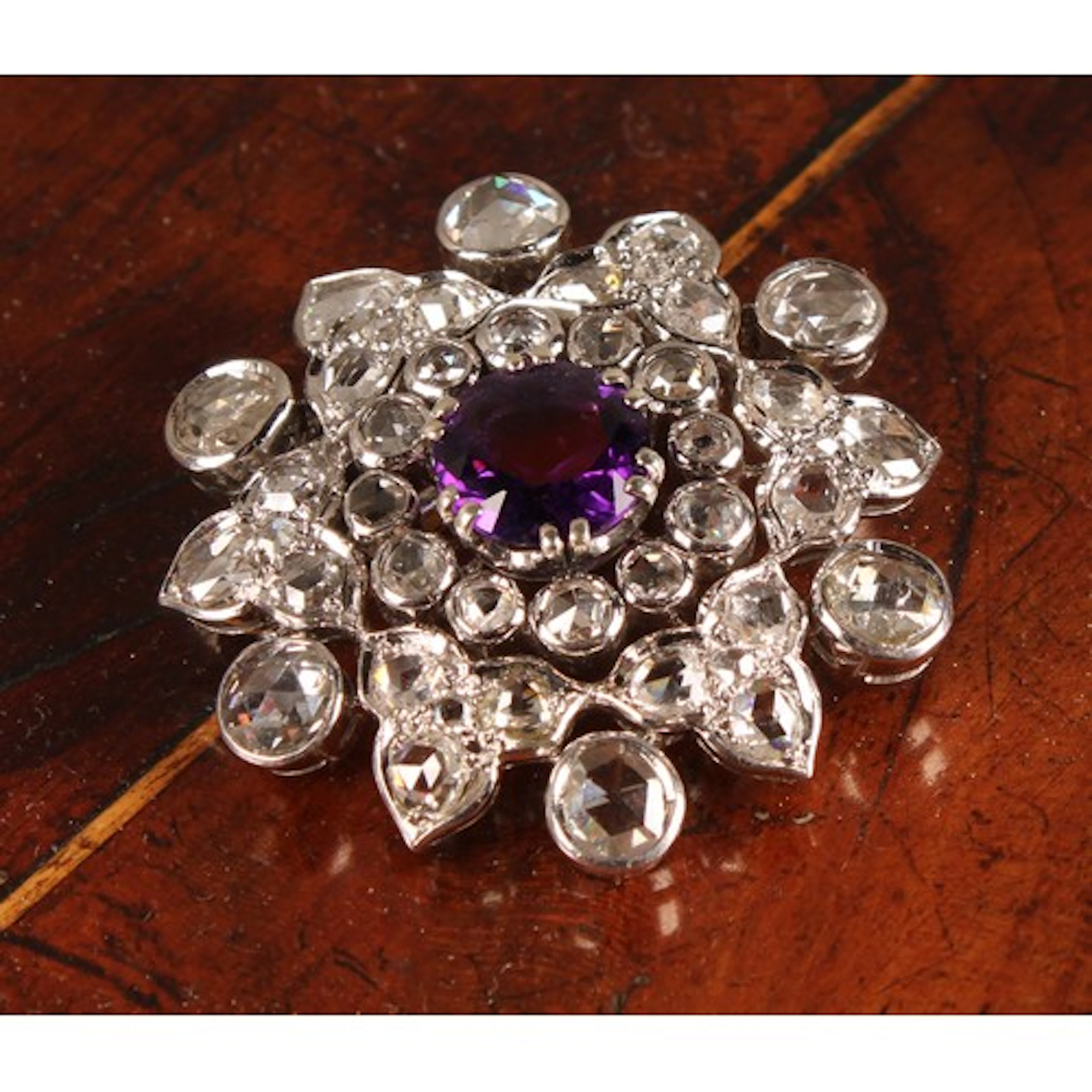 A diamond and amethyst floral cluster brooch, with central v...