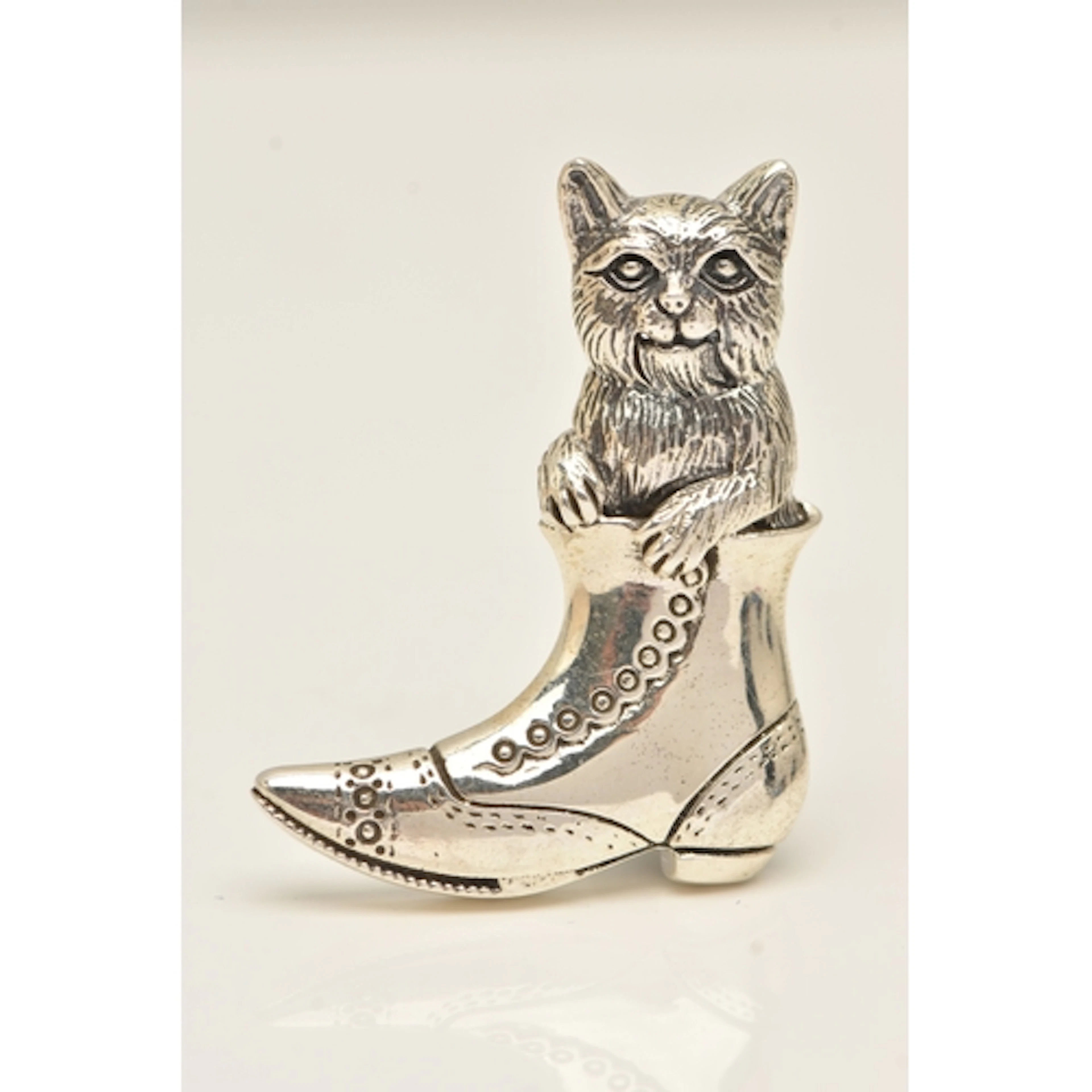 A WHITE METAL BROOCH, in the form of a cat in a boot, fitted...
