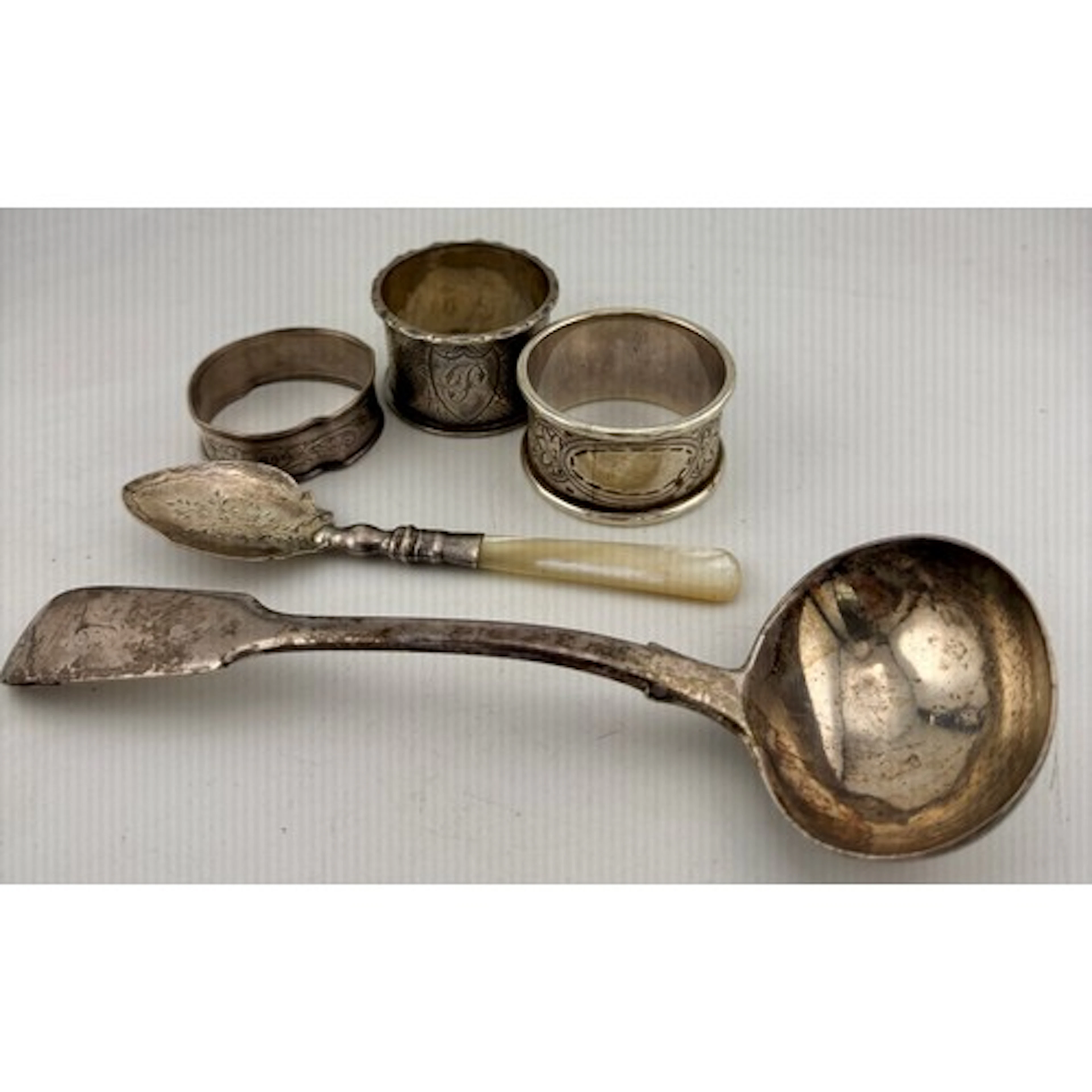 Three silver napkins rings, a ladle, London 1838 and a mothe...