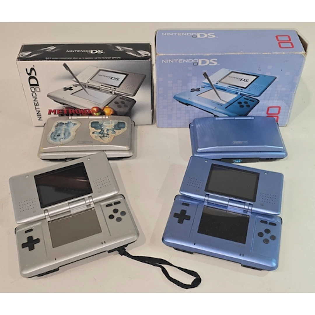 A collection of four Nintendo DS handheld consoles. Two are ...