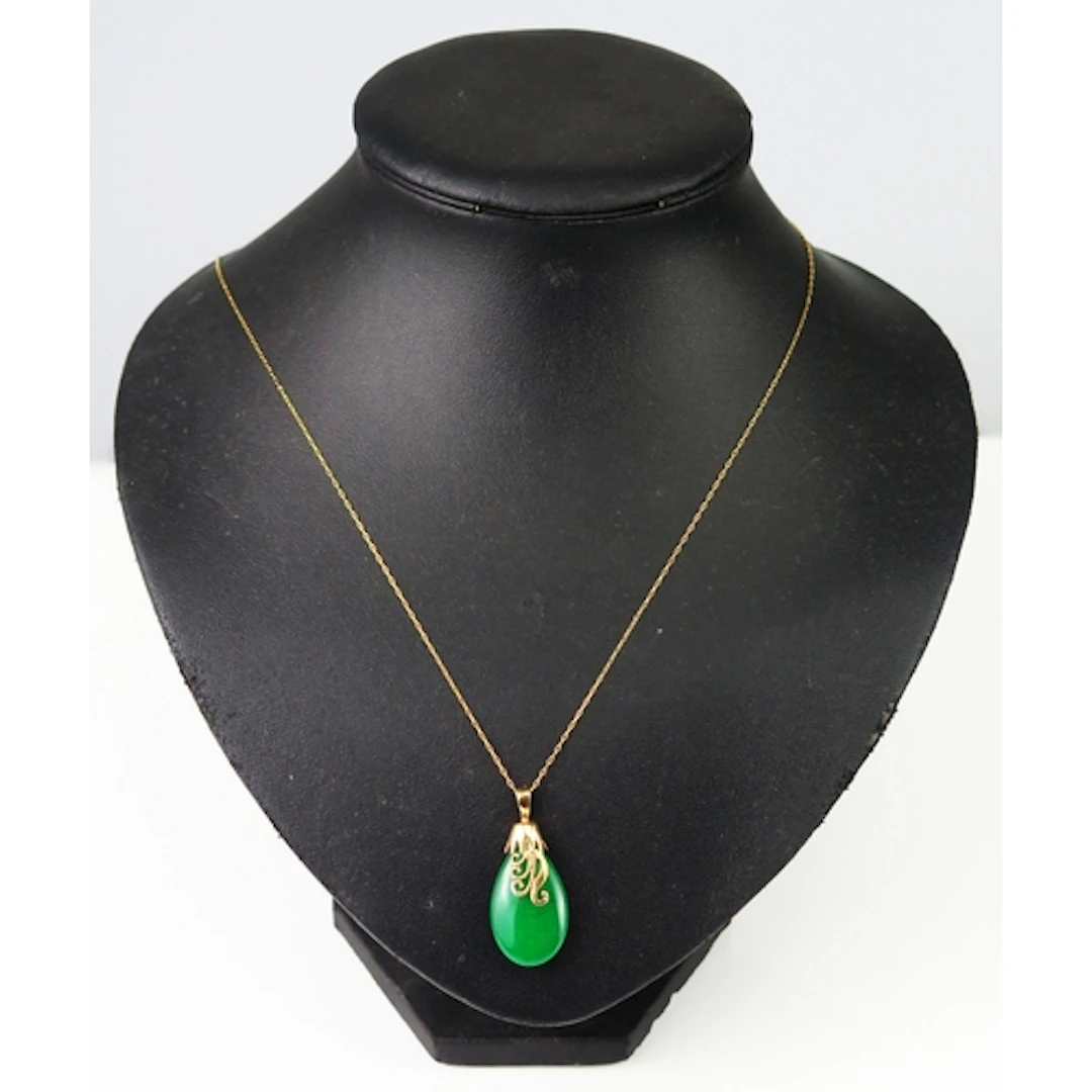A jade pendant in a yellow ,metal mount and on a 14K gold ch...