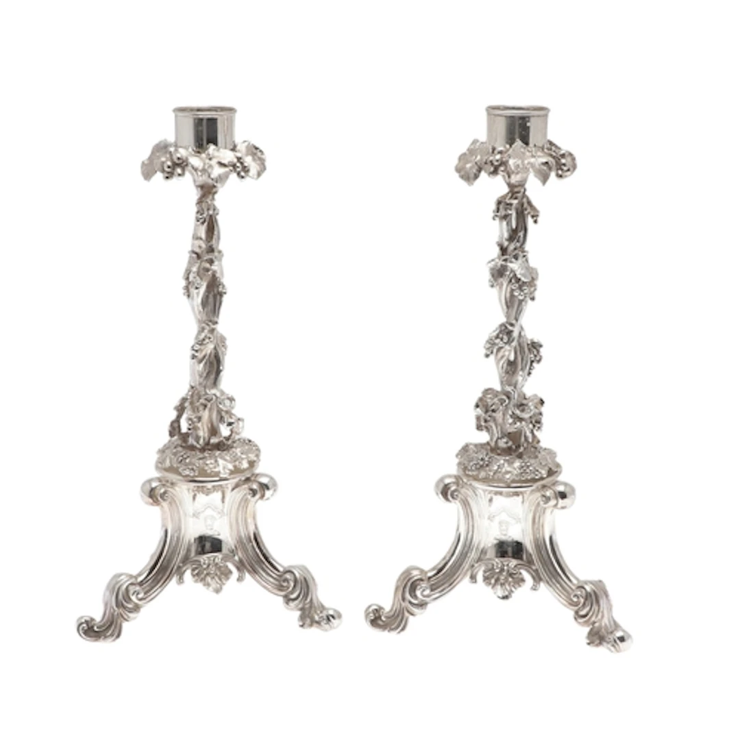 A PAIR OF ORNATE SILVER PLATED CAST CANDLESTICKS. The capita...