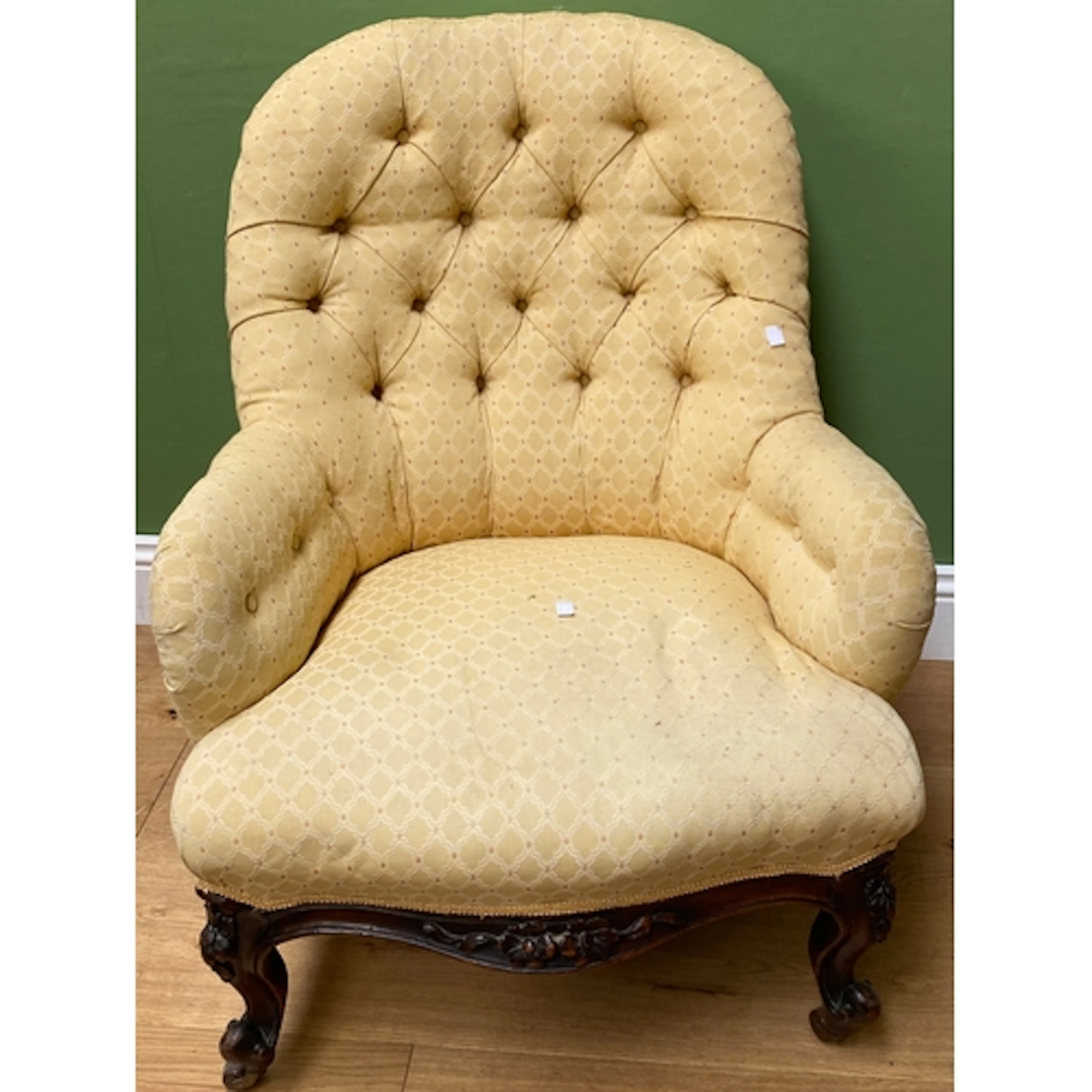 A yellow button upholstered armchair with carved frame with ...