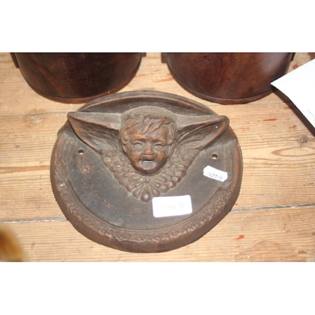 Cast iron wall plaque depicting a mythical face.