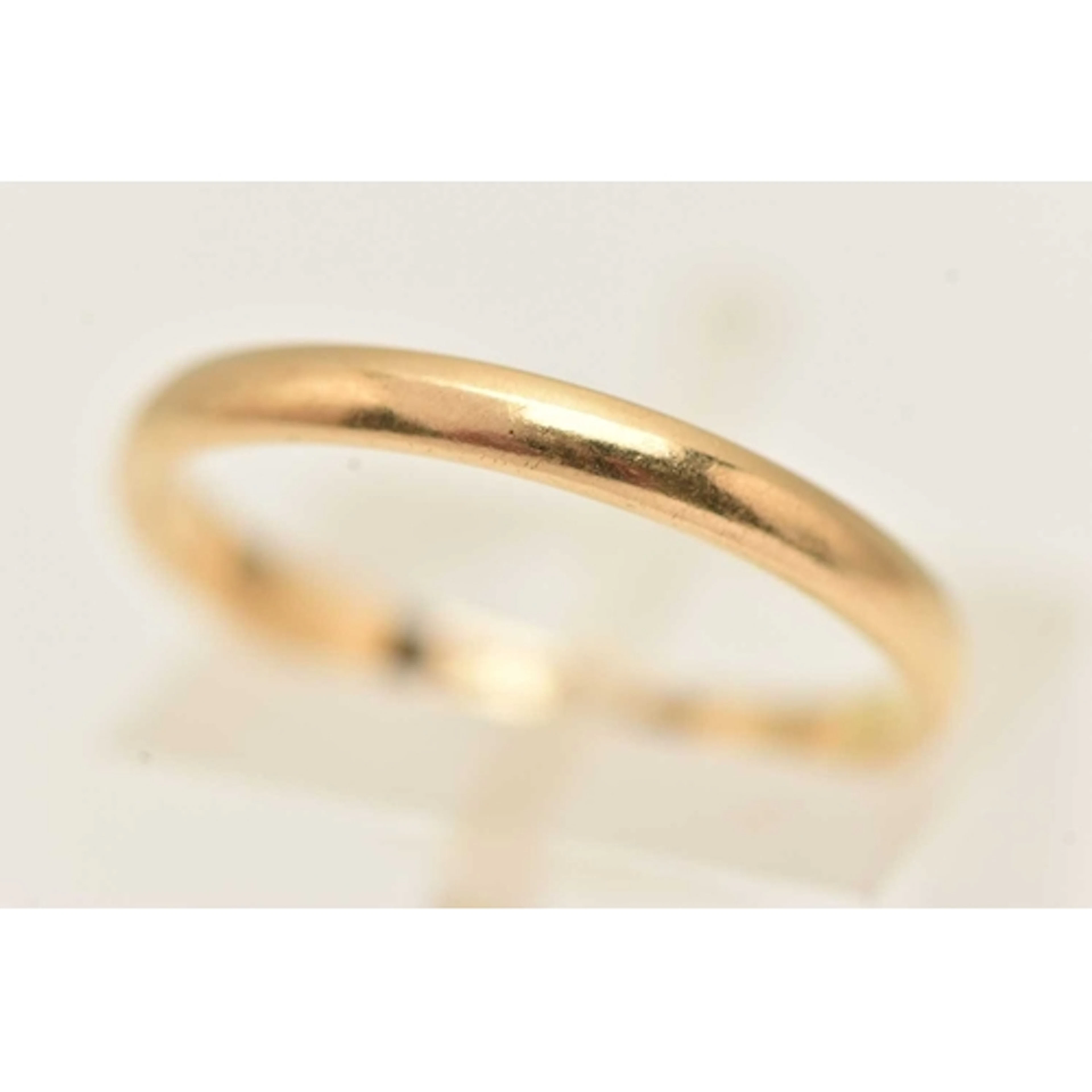 A YELLOW METAL BAND RING, of plain polished design, stamped ...