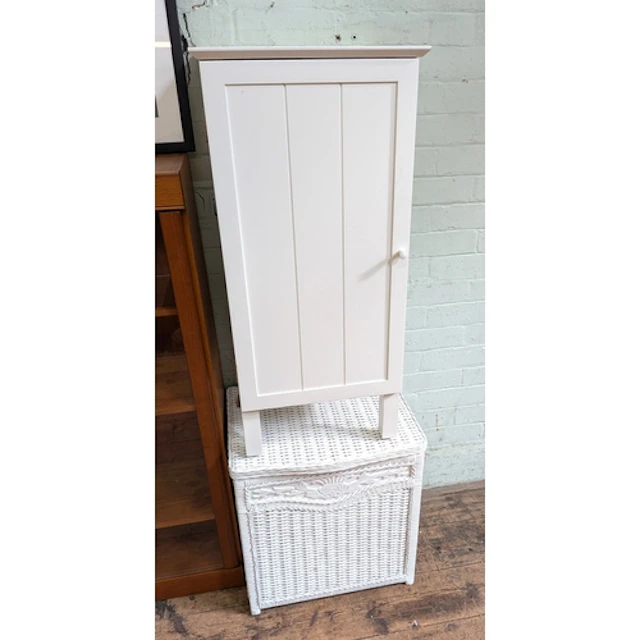 A white painted wicker linen basket and a white bedside cabi...
