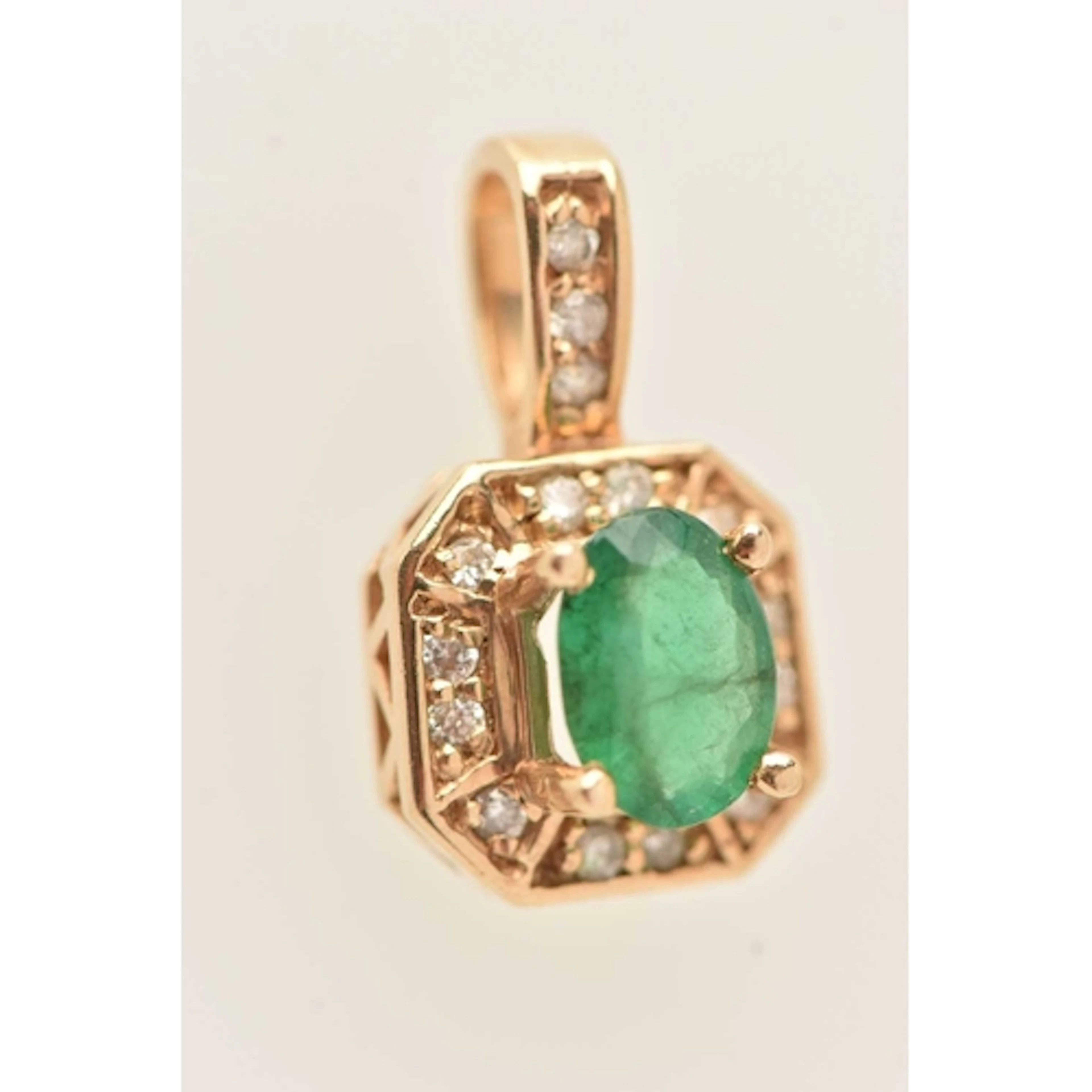 A YELLOW METAL EMERALD PENDANT, an oval cut emerald, set wit...