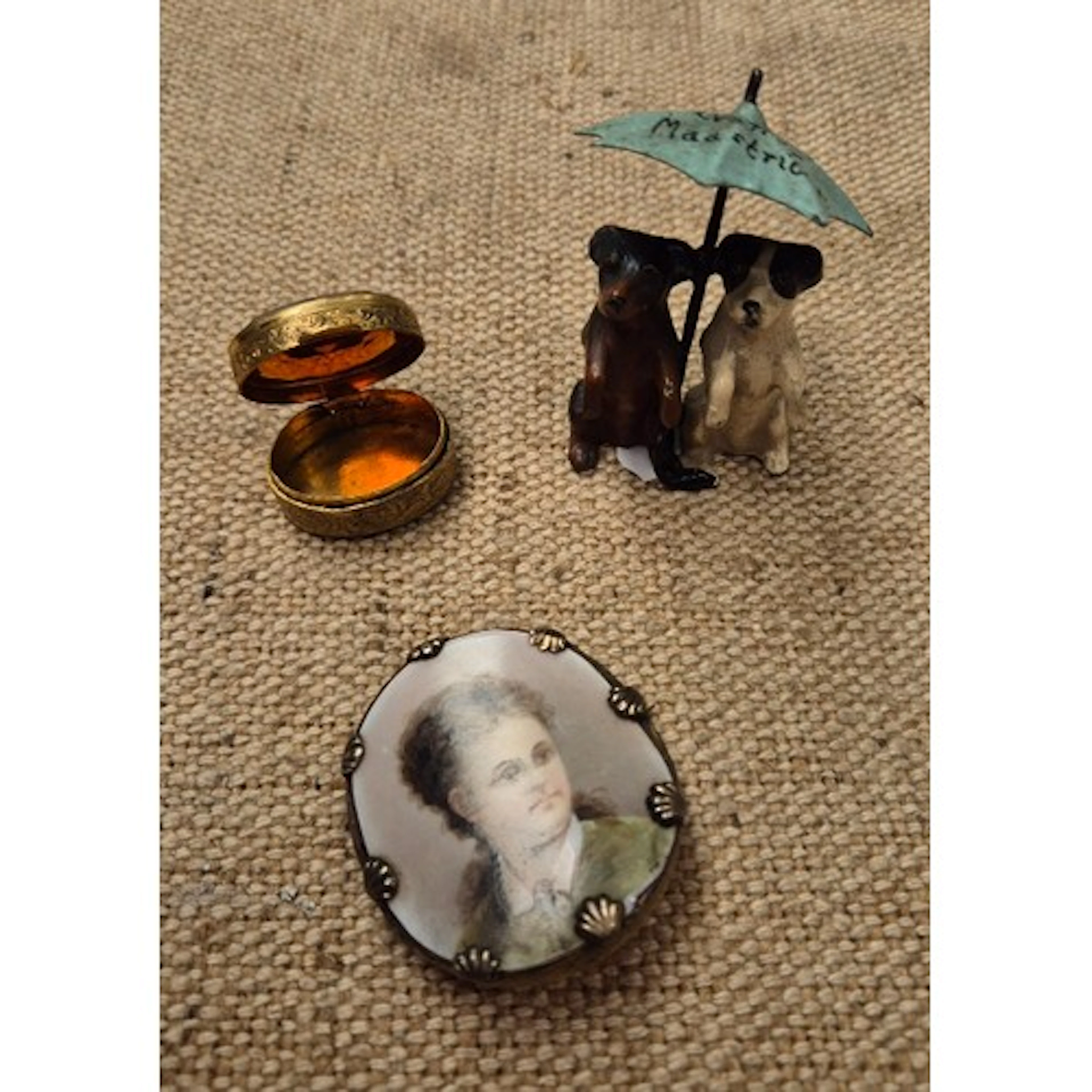 A small metal figurine featuring 2 dogs sheltering under an ...
